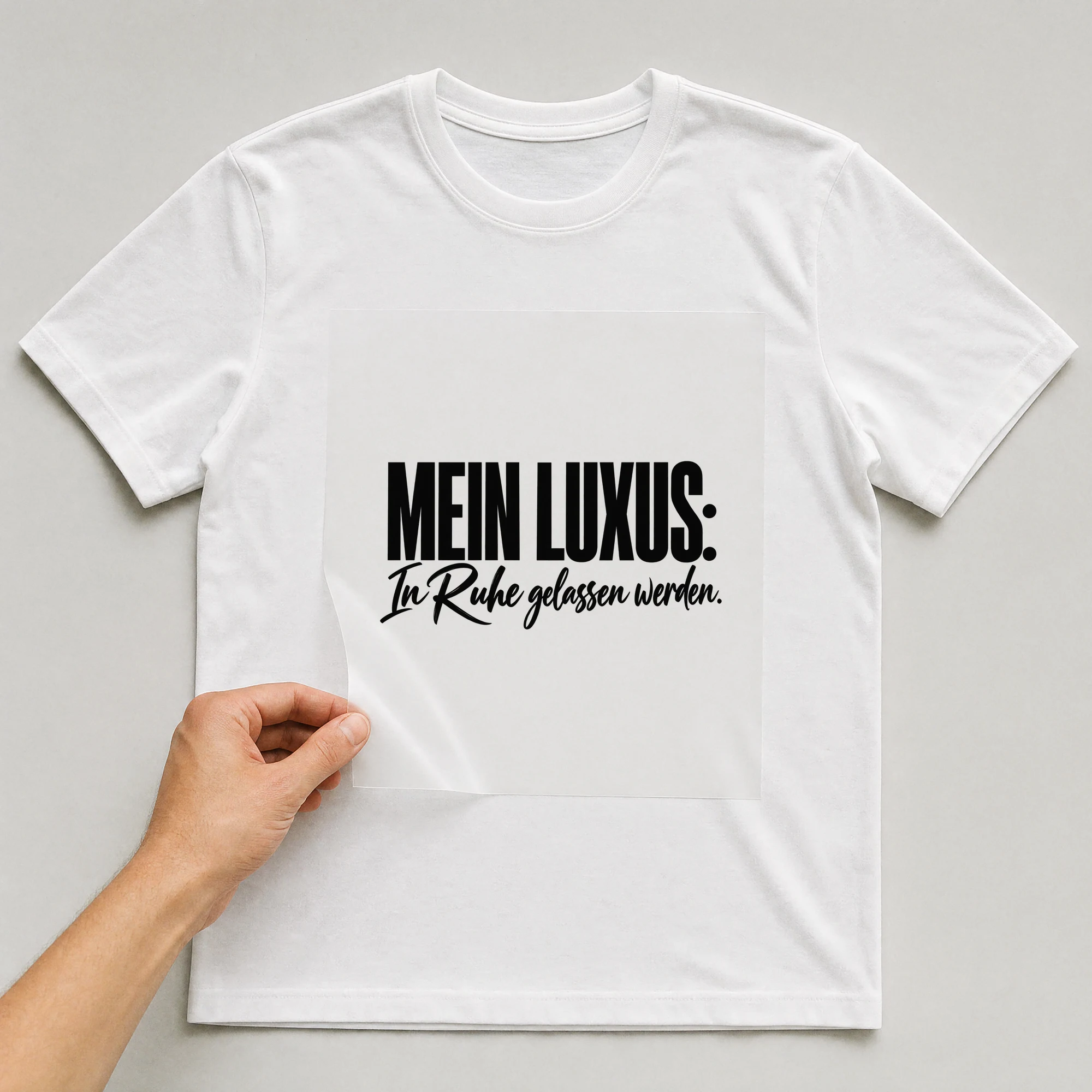 Bügelbild „Mein Luxus: In Ruhe gelassen werden.“ auf weißem T-Shirt, Folie wird aufgelegt