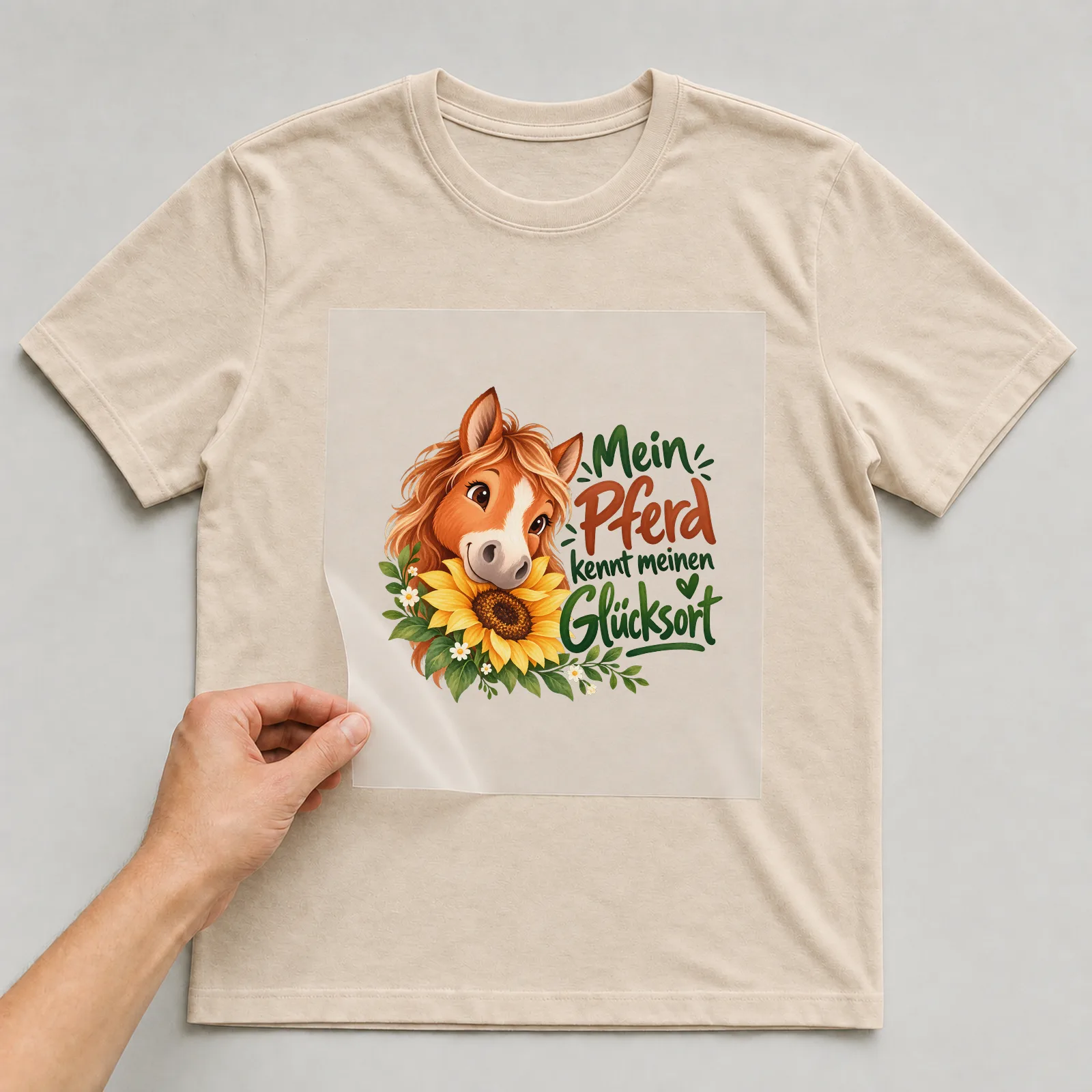 Bügelbild „Mein Pferd kennt meinen Glücksort“ auf beigem T-Shirt, Folie wird aufgelegt
