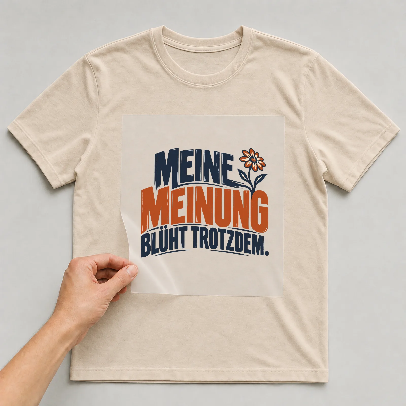 Bügelbild „Meine Meinung blüht trotzdem“ auf beigem T-Shirt, Folie wird aufgelegt