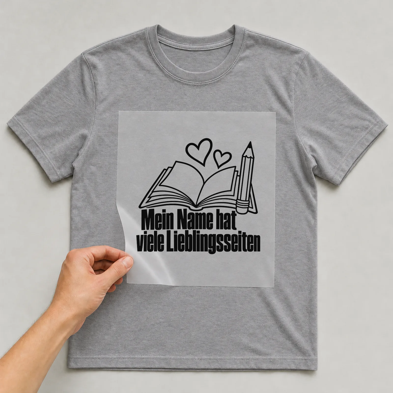 Bügelbild „Mein Name hat viele Lieblingsseiten“ auf grauem T-Shirt, Folie wird aufgelegt
