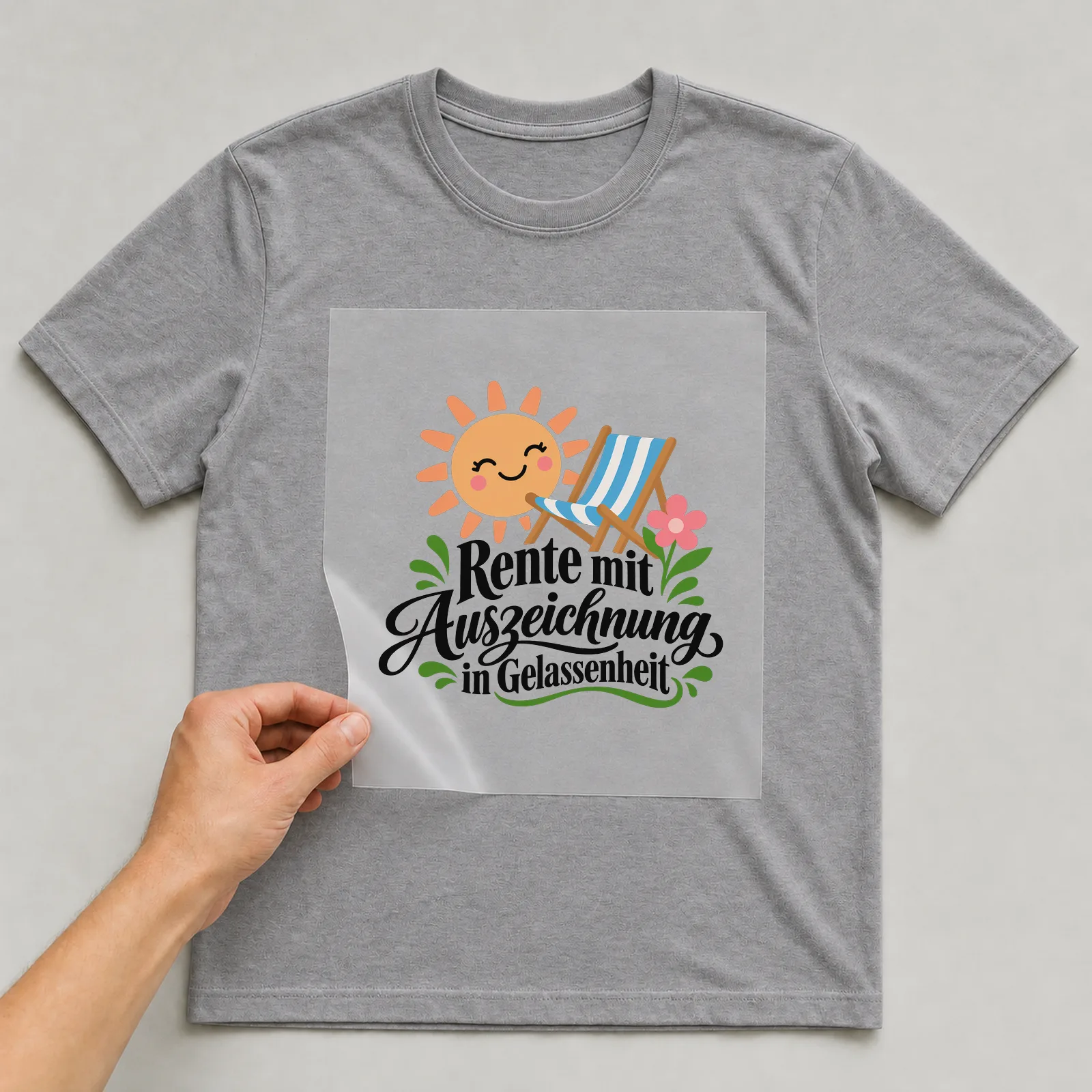 Bügelbild „Rente mit Auszeichnung in Gelassenheit“ auf grauem T-Shirt, Folie wird aufgelegt