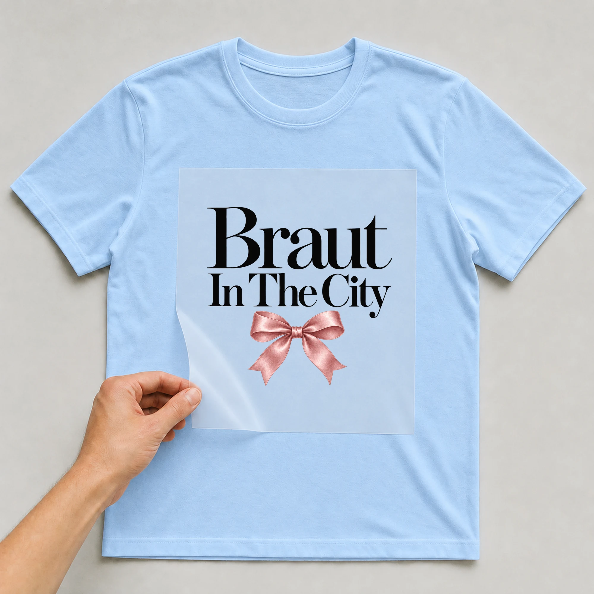 Bügelbild „Braut In The City“ auf babyblauem T-Shirt, Folie wird aufgelegt