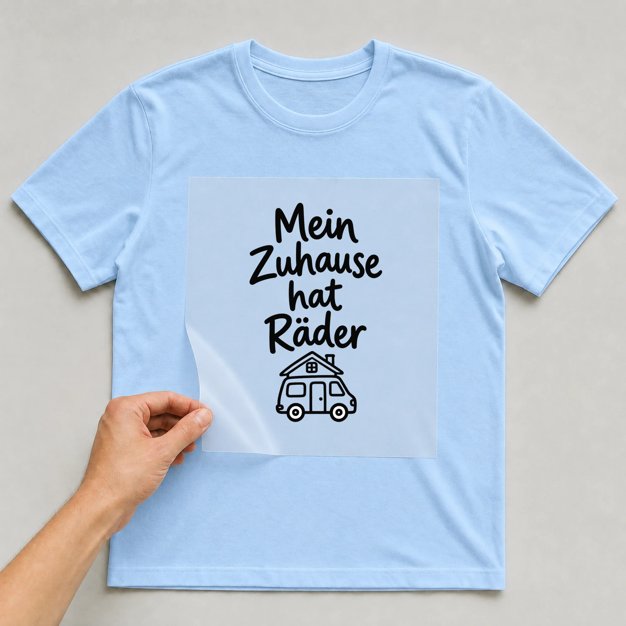 Bügelbild „Mein zuhause hat raeder“ auf babyblauem T-Shirt, Folie wird aufgelegt
