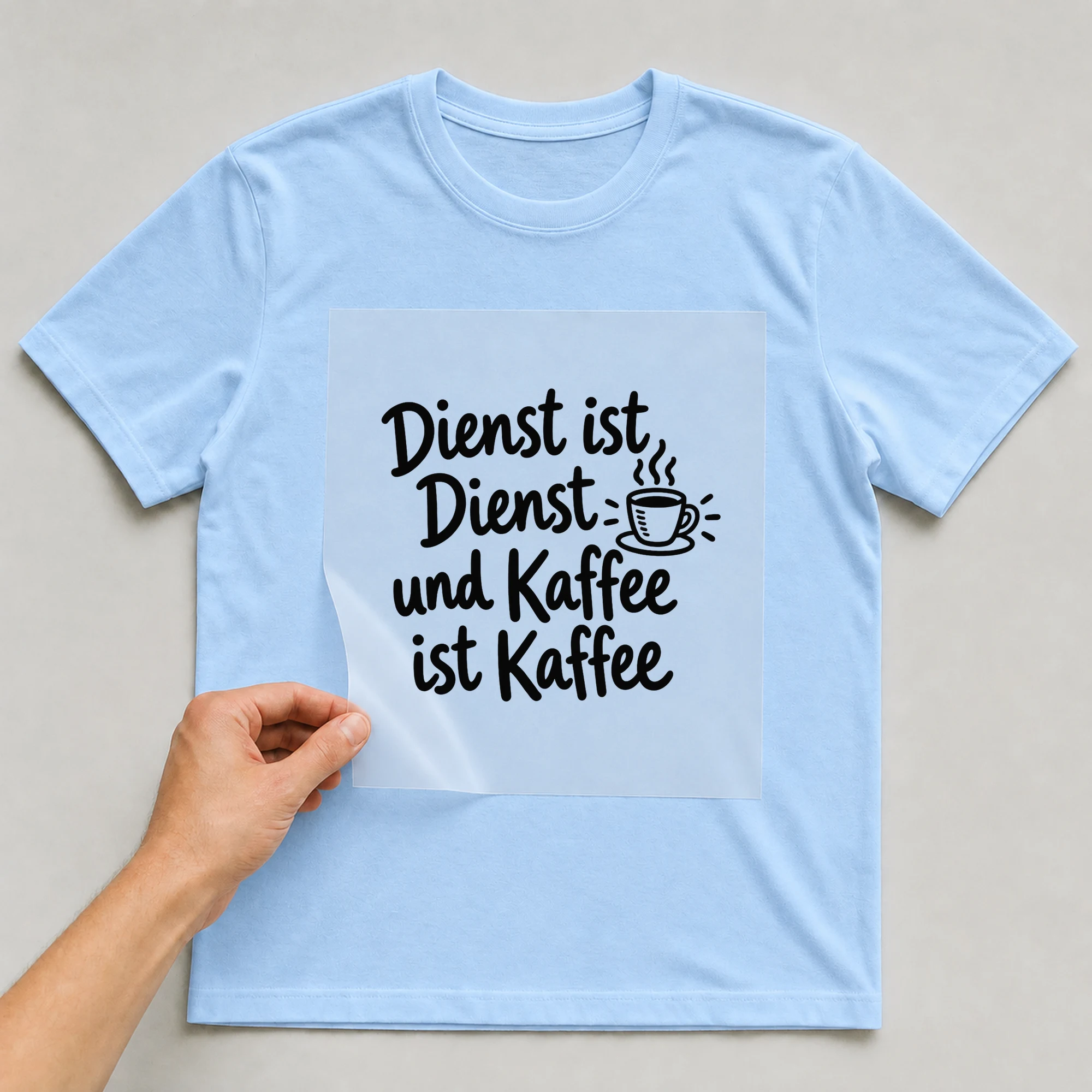Bügelbild „Dienst ist Dienst und Kaffee ist Kaffee“ auf babyblauem T-Shirt, Folie wird aufgelegt