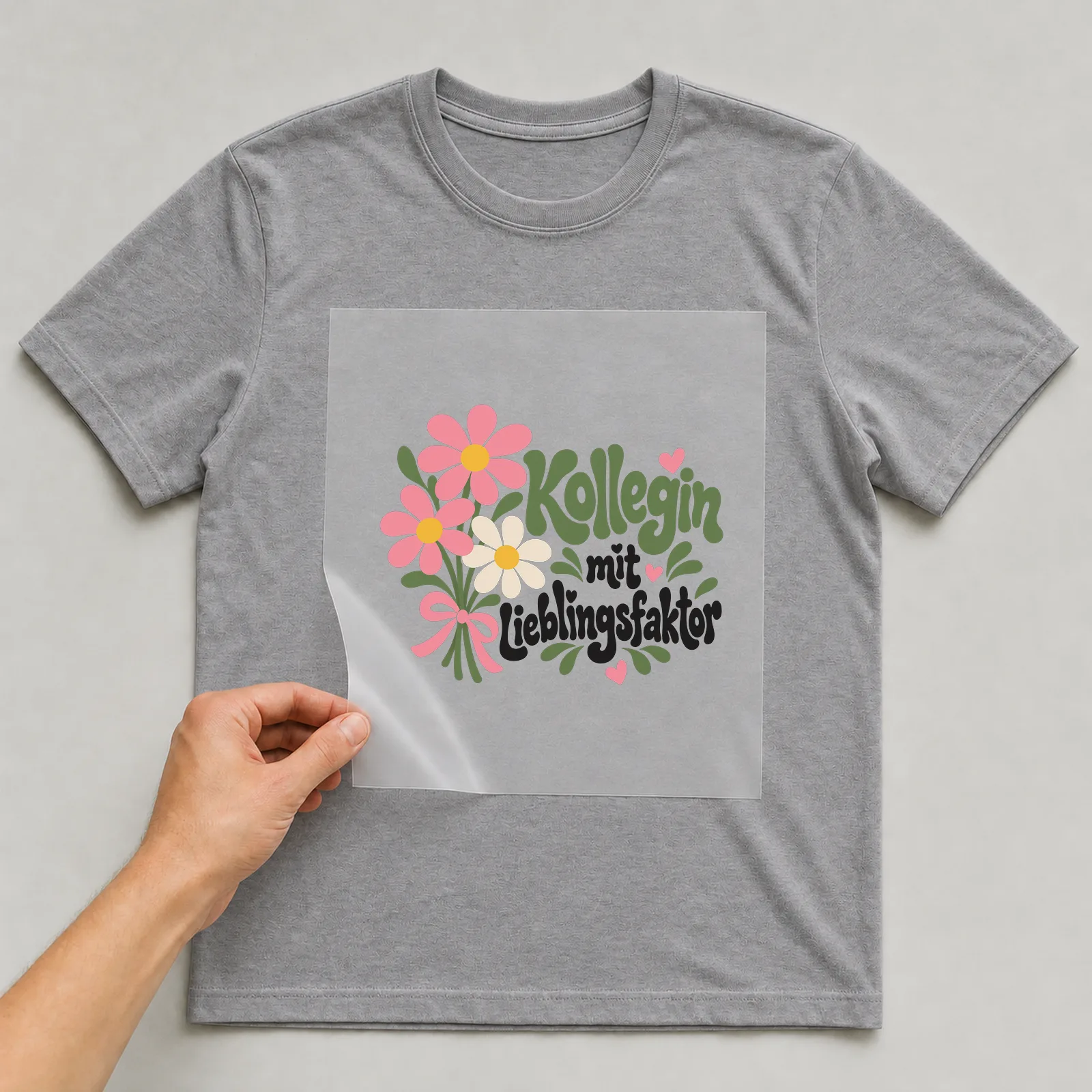 Bügelbild „Kollegin mit Lieblingsfaktor“ auf grauem T-Shirt, Folie wird aufgelegt