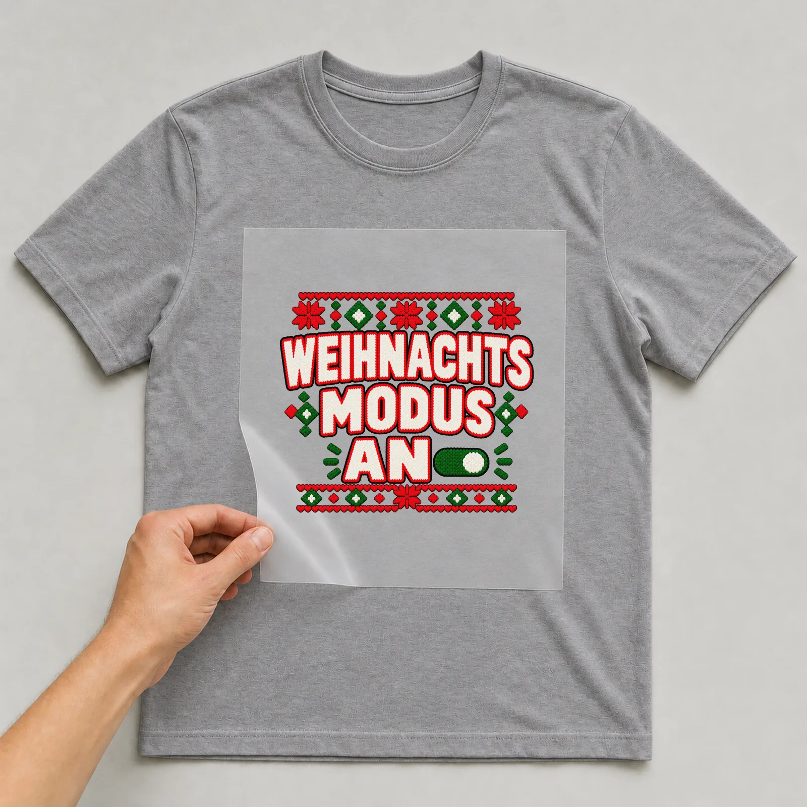 Bügelbild Weihnachtsmodus an auf grauem T-Shirt, Folie wird aufgelegt