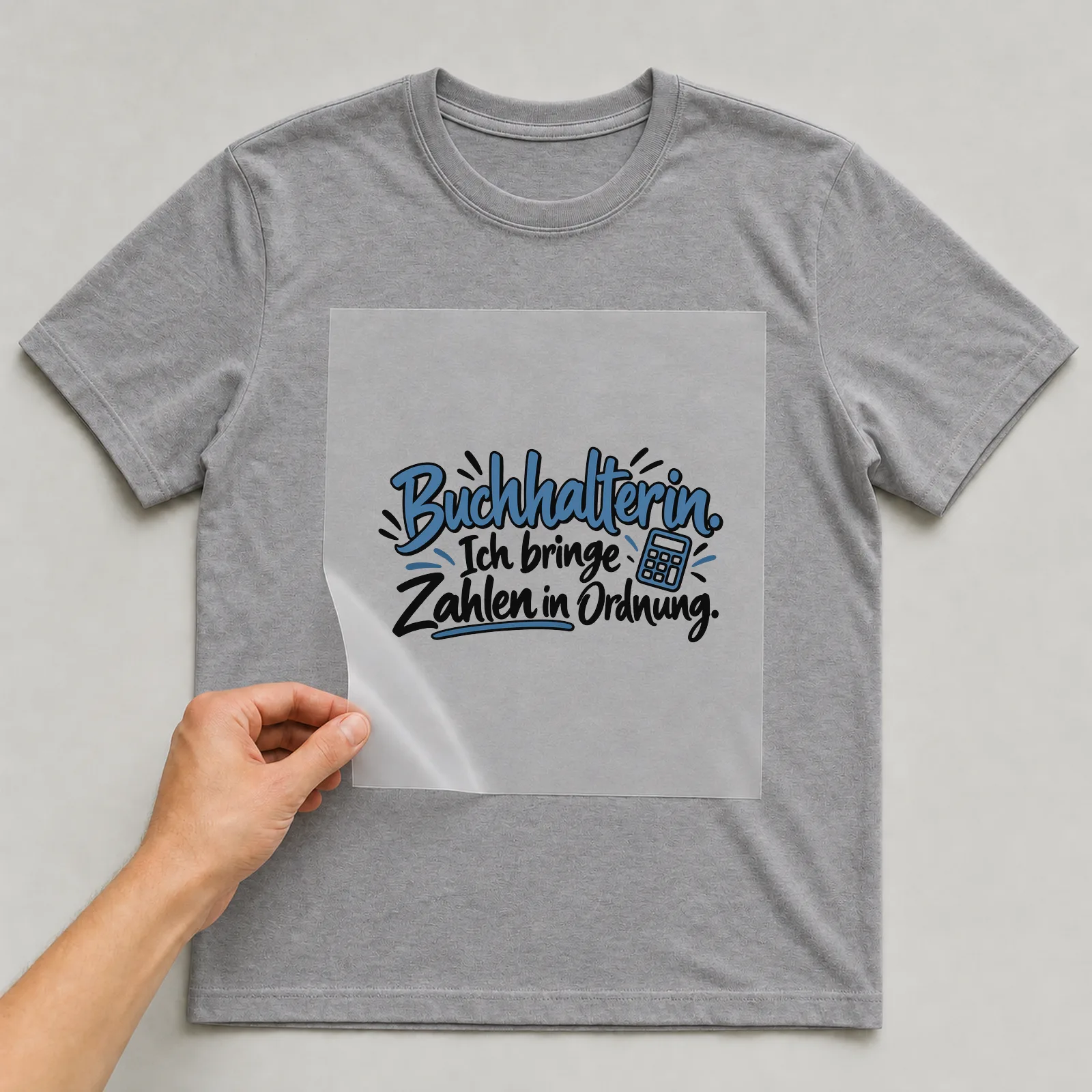 Bügelbild „Buchhalterin. Ich bringe Zahlen in Ordnung.“ auf grauem T-Shirt, Folie wird aufgelegt
