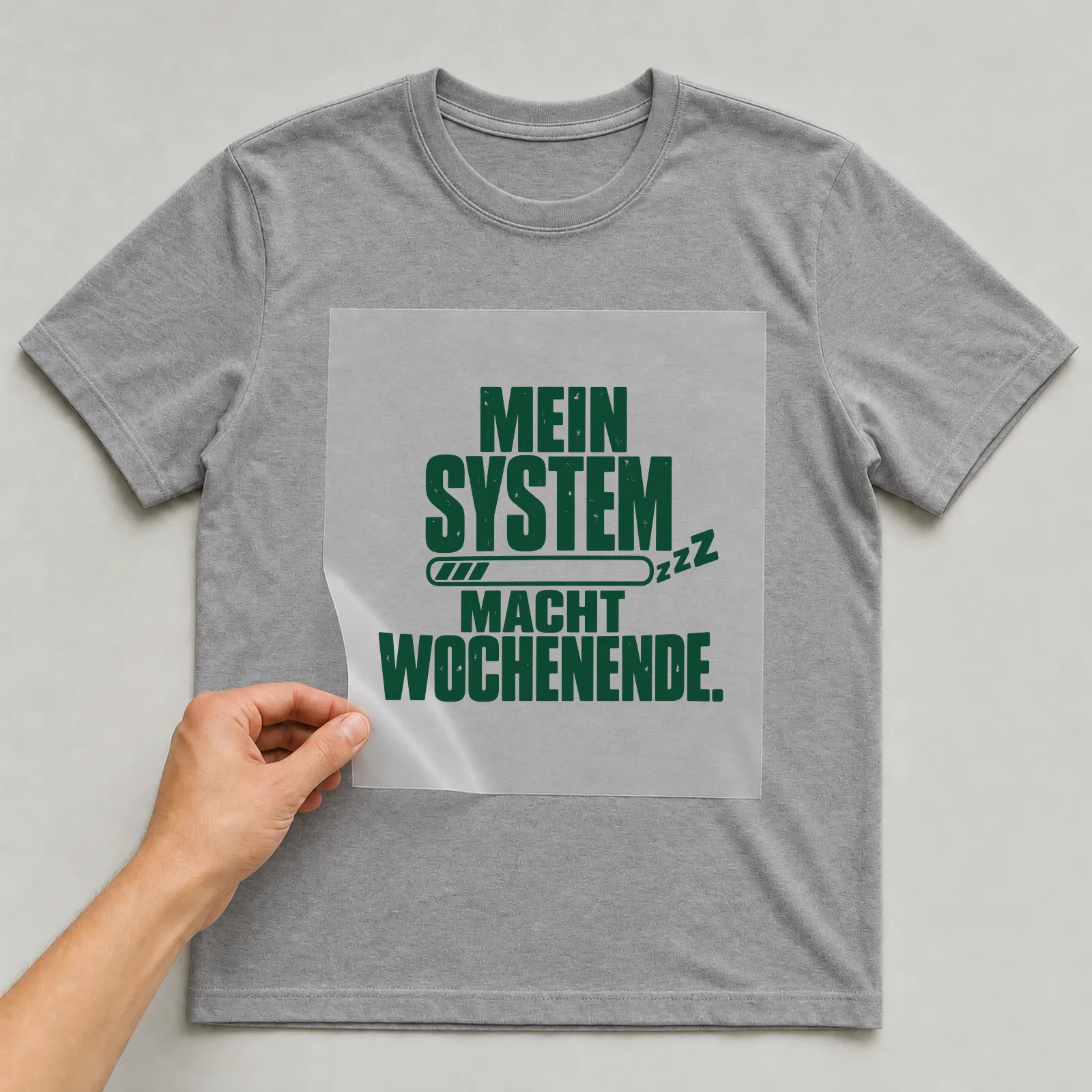 Bügelbild „Mein System macht Wochenende“ auf grauem T-Shirt, Folie wird aufgelegt