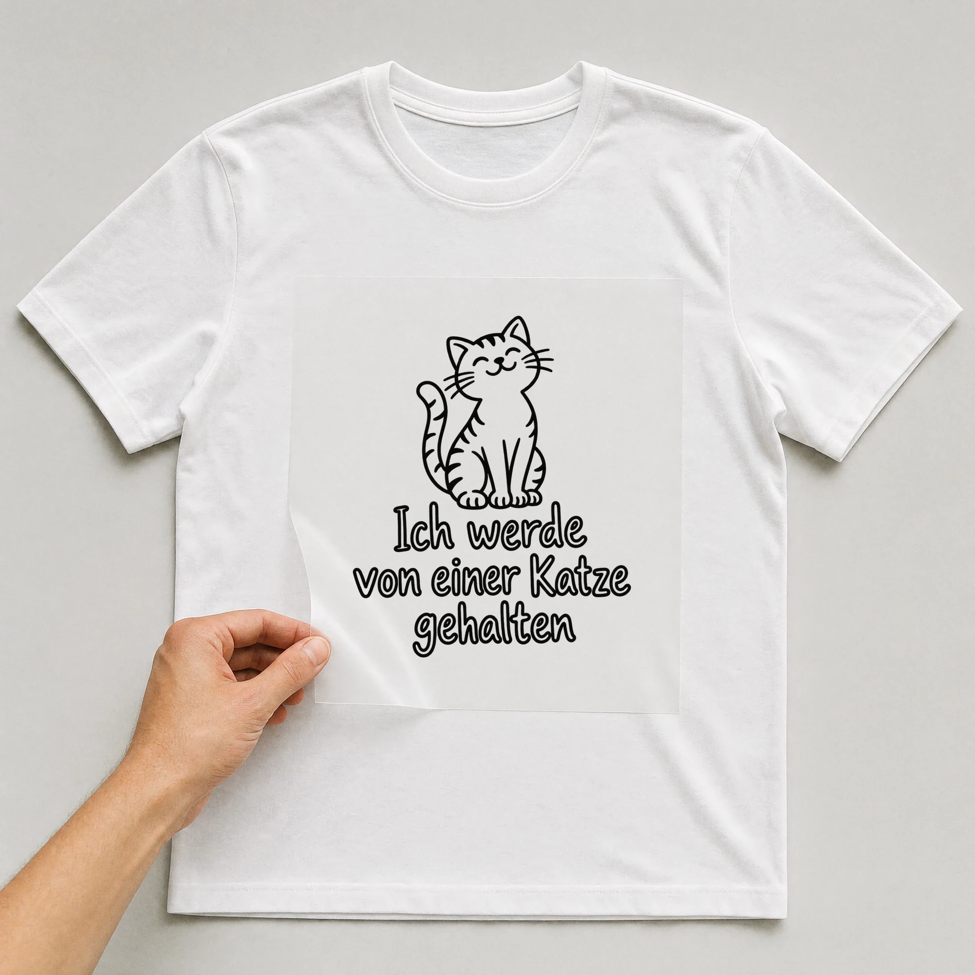 Bügelbild „Ich werde von einer Katze gehalten“ auf weißem T-Shirt, Folie wird aufgelegt