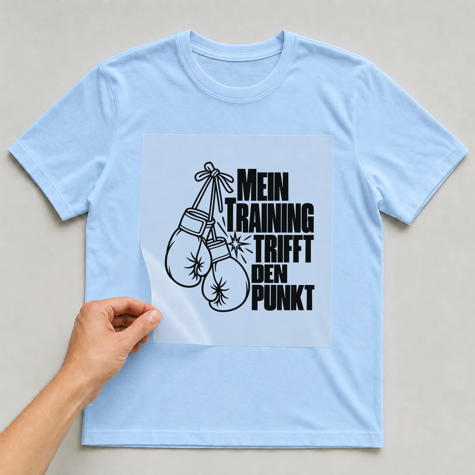 Bügelbild „Mein Training trifft den Punkt“ auf hellblauem T-Shirt, Folie wird aufgelegt