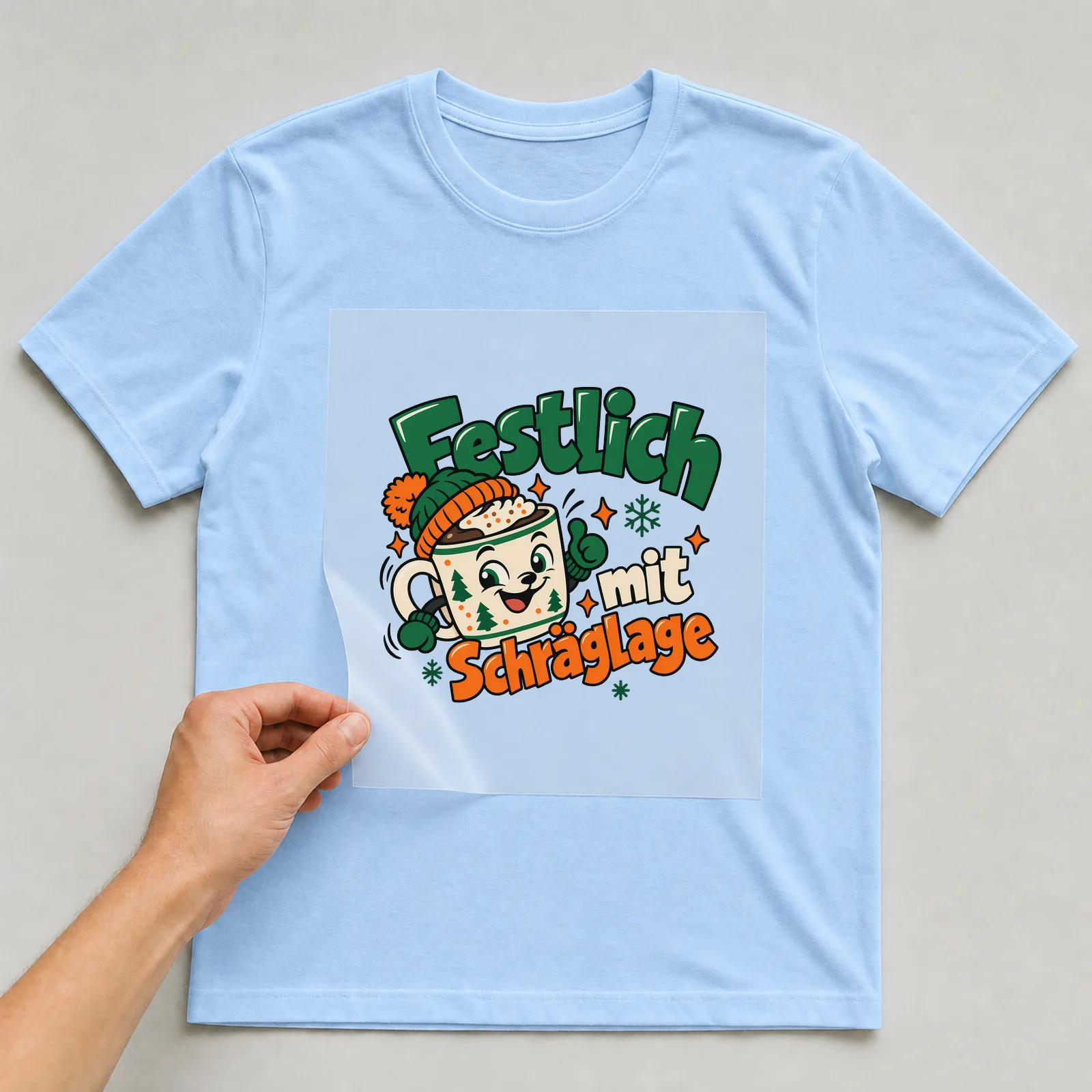 Bügelbild „Festlich mit Schräglage“ auf hellblauem T-Shirt, Folie wird aufgelegt