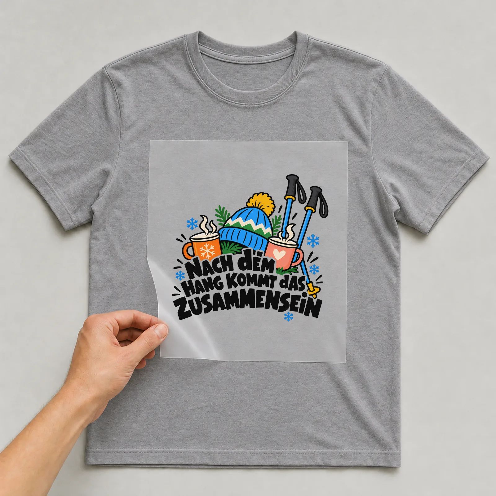 Bügelbild „Nach dem Hang kommt das Zusammensein“ auf grauem T-Shirt, Folie wird aufgelegt