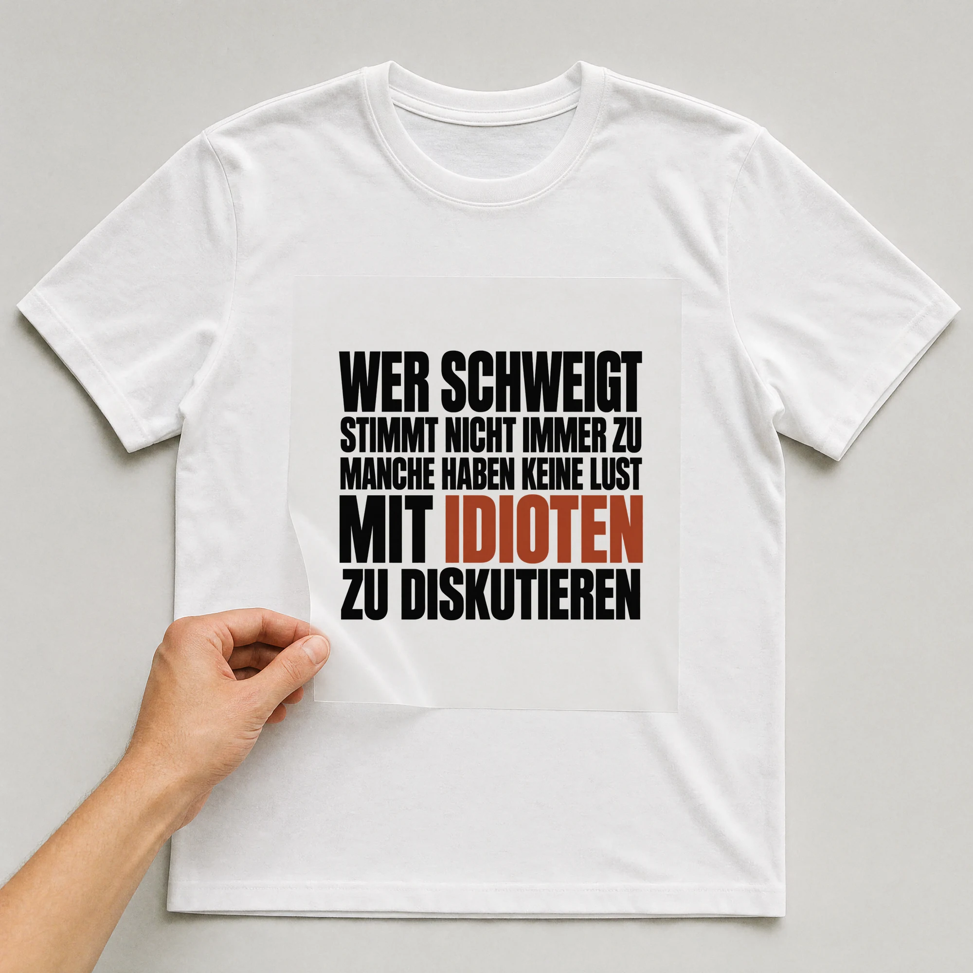 Bügelbild „Wer schweigt stimmt nicht immer zu manche haben keine Lust mit Idioten zu“ auf weißem T-Shirt, Folie wird aufgelegt