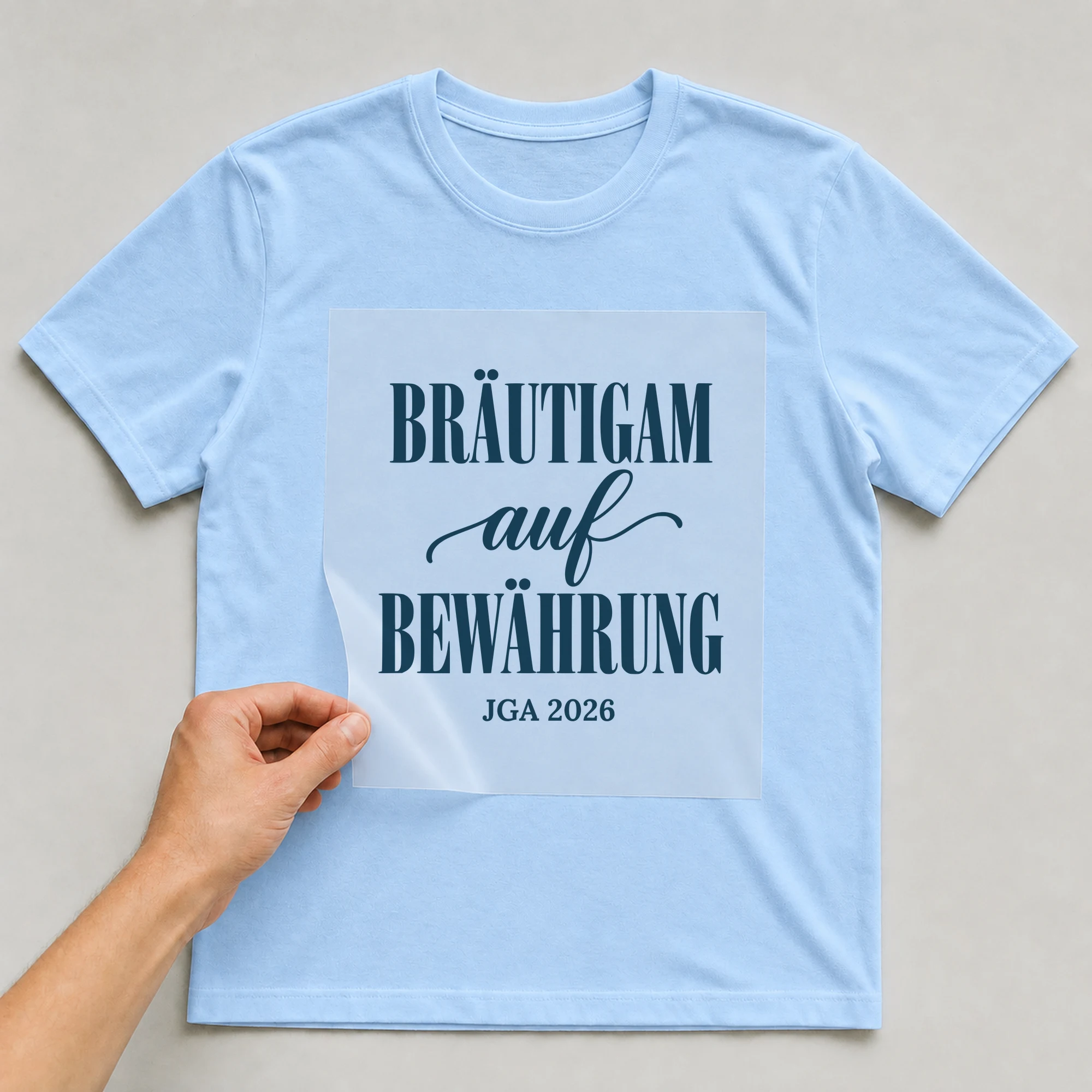 Bügelbild Bräutigam auf Bewährung auf hellblauem T-Shirt, Folie wird aufgelegt