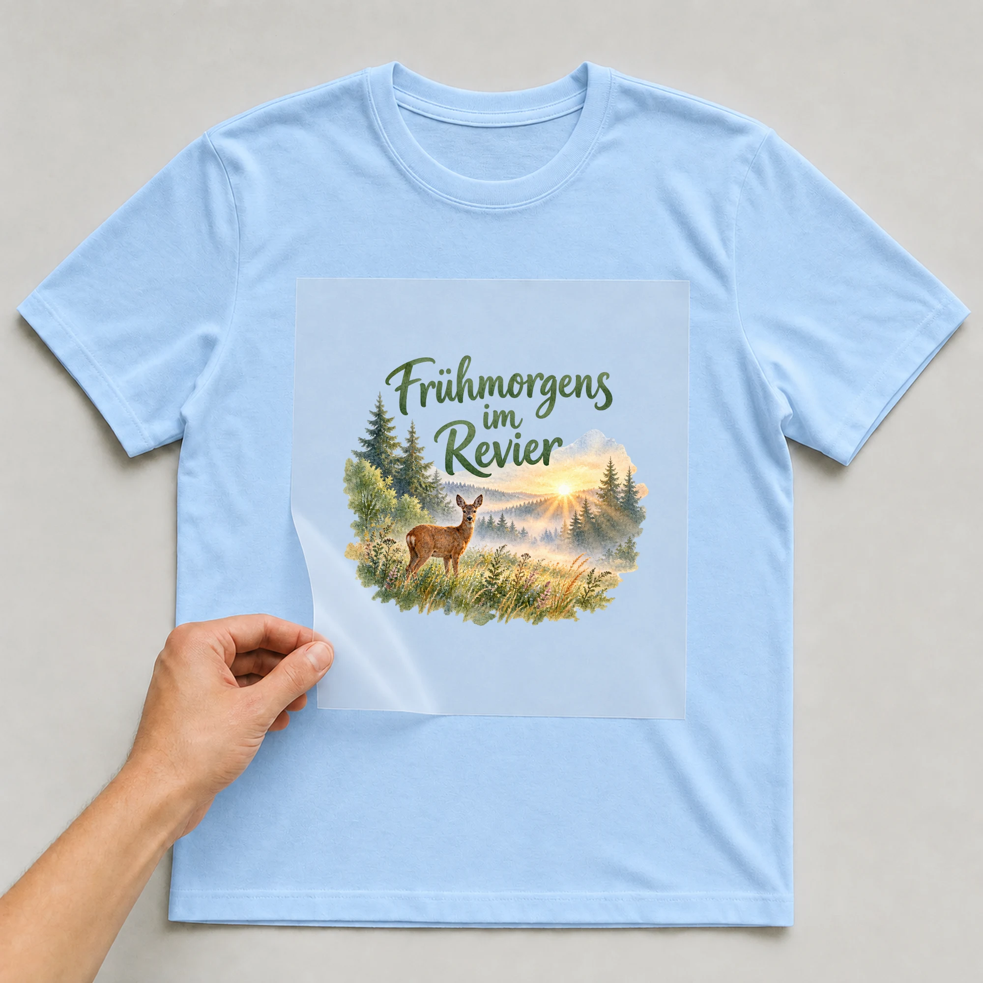 Bügelbild „Frühmorgens im Revier“ auf babyblauem T-Shirt, Folie wird aufgelegt