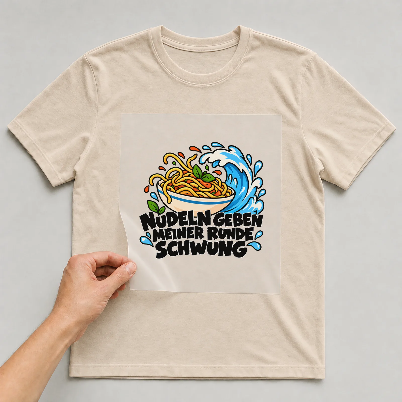 Bügelbild „Nudeln geben meiner Runde Schwung“ auf beigem T-Shirt, Folie wird aufgelegt