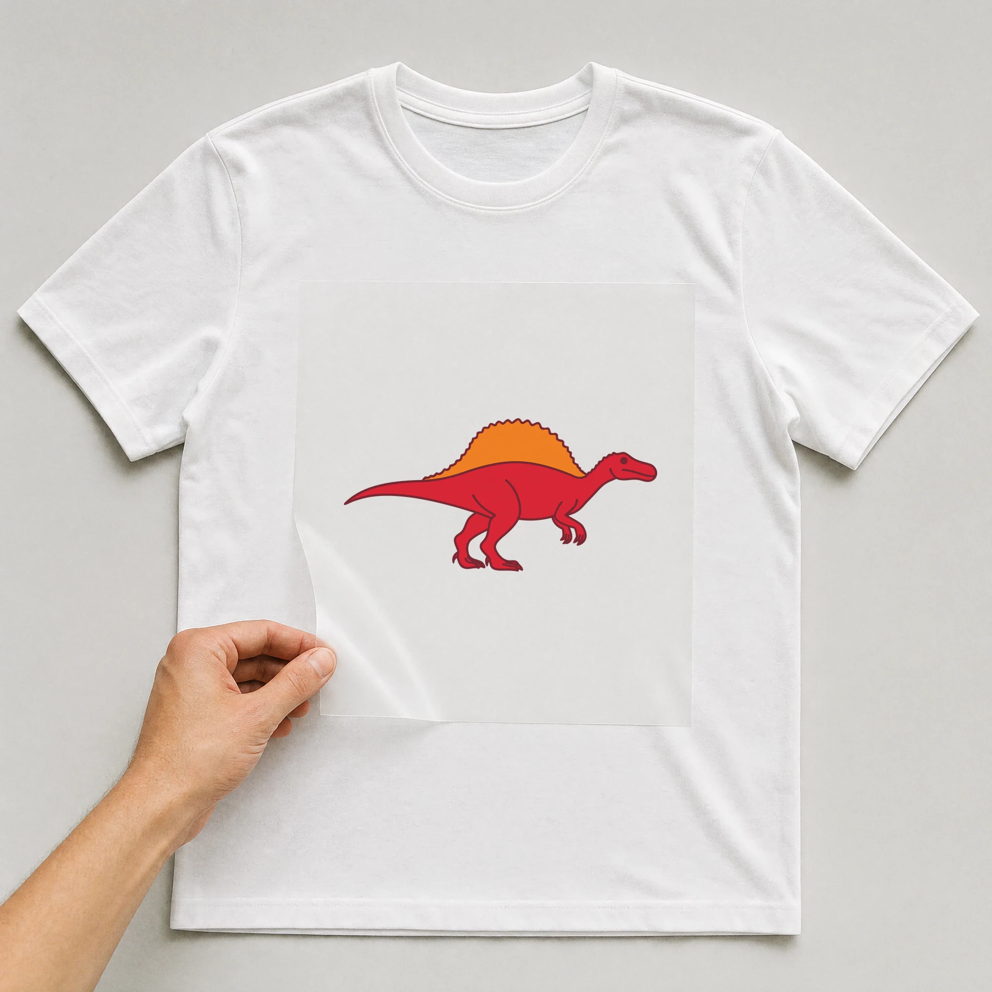 Bügelbild „Dino Spinosaurus“ auf weißem T-Shirt, Folie wird aufgelegt