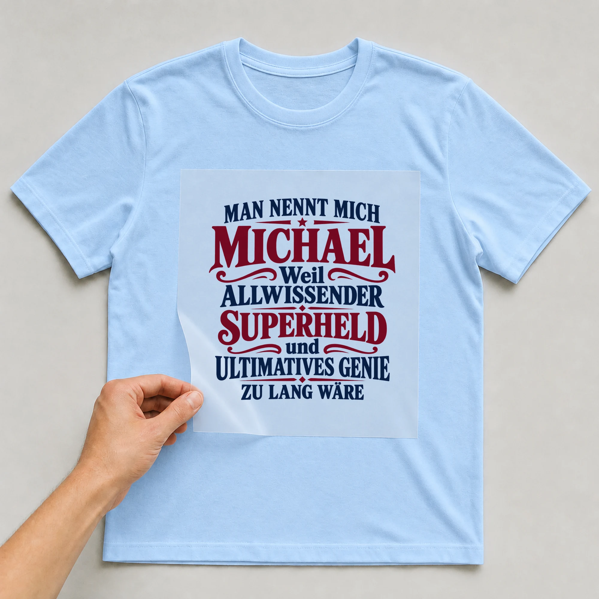 Bügelbild „Man nennt mich Michael weil allwissender Superheld und ultimatives Genie zu“ auf babyblauem T-Shirt, Folie wird aufgelegt