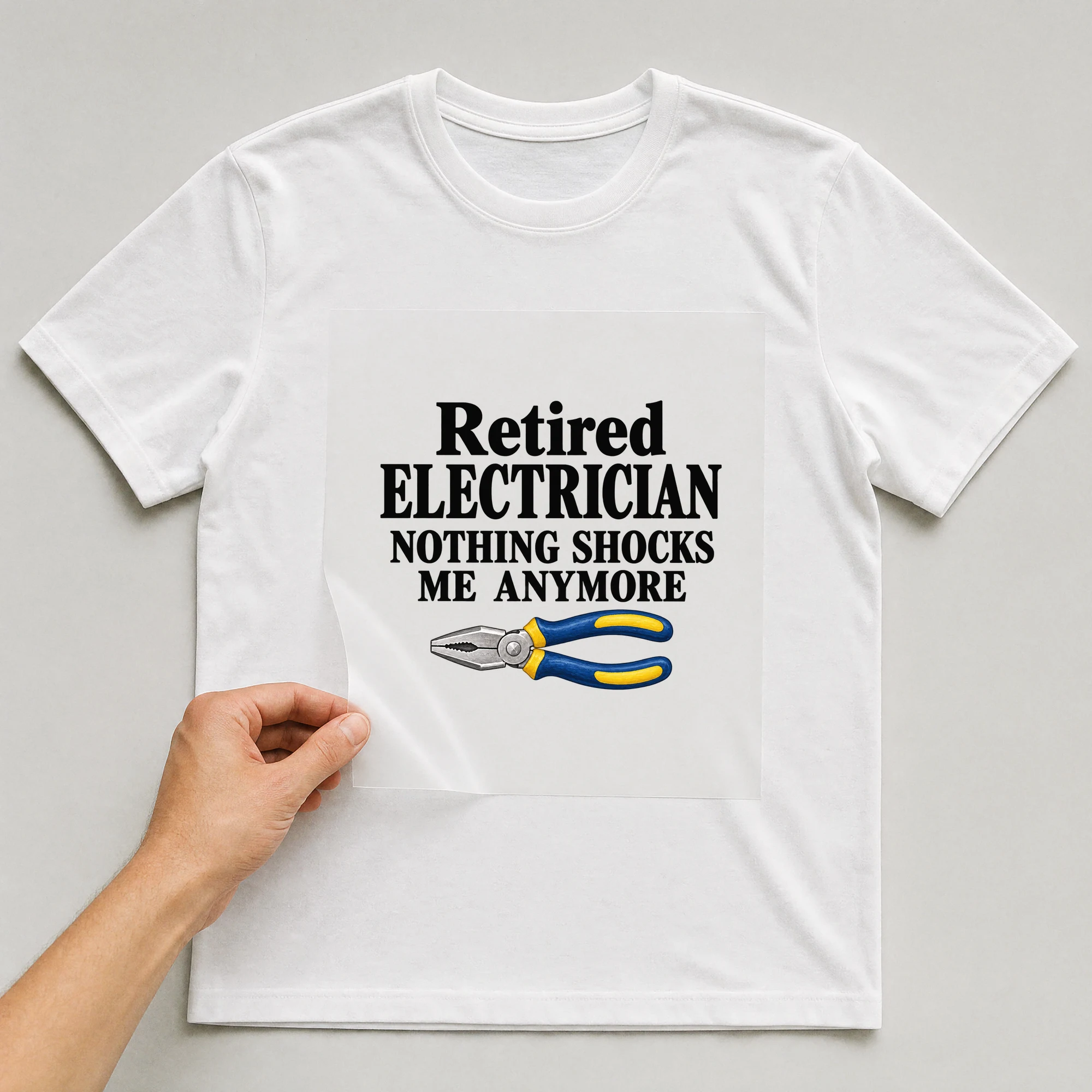 Bügelbild „Retired Electrician Nothing Shocks Me Anymore“ auf weißem T-Shirt, Folie wird aufgelegt