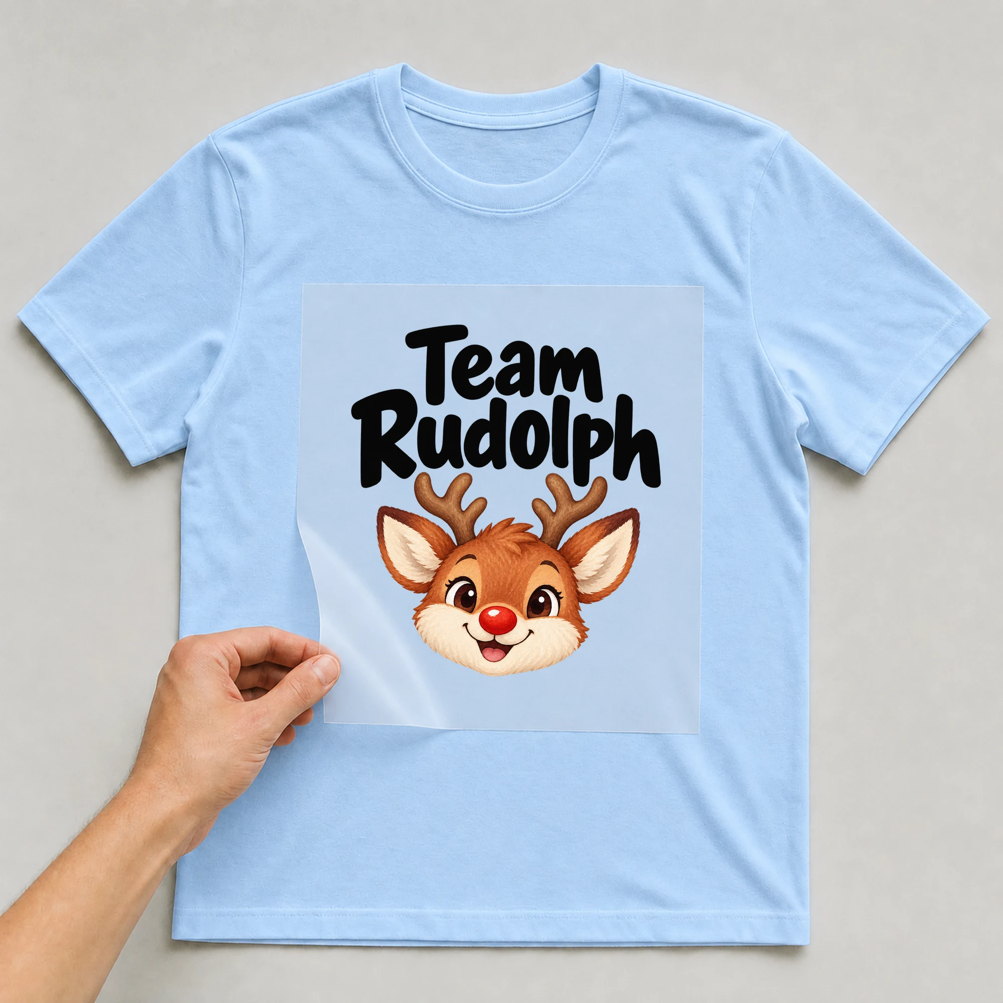 Bügelbild „Team Rudolph“ auf babyblauem T-Shirt, Folie wird aufgelegt