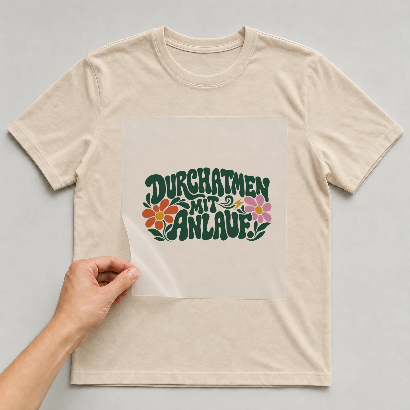 Bügelbild „Durchatmen mit Anlauf“ auf beigem T-Shirt, Folie wird aufgelegt