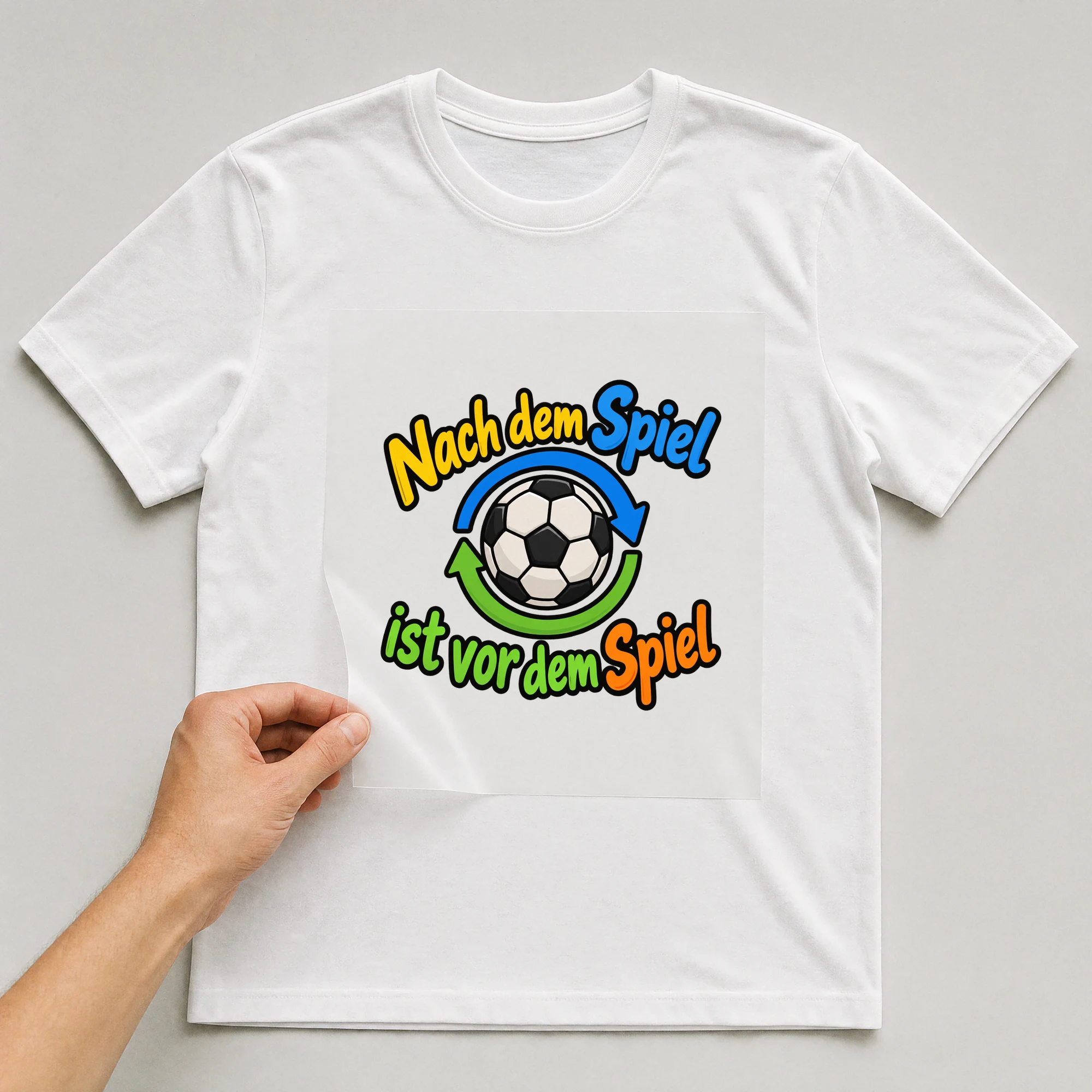 Bügelbild „Nach dem Spiel ist vor dem Spiel“ auf weißem T-Shirt, Folie wird aufgelegt