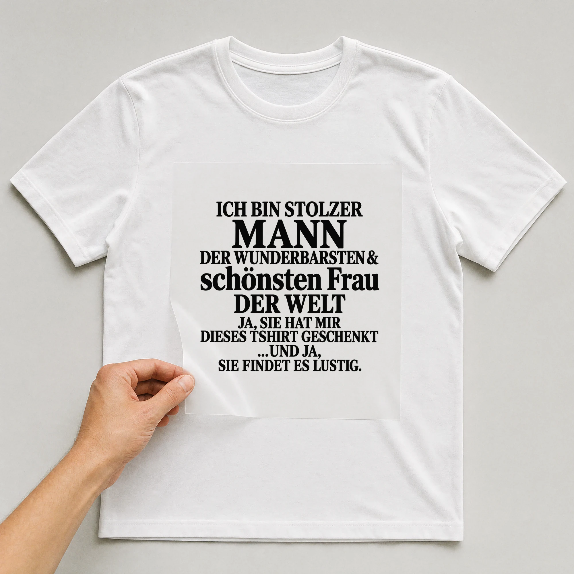 Bügelbild „Ich bin stolzer Mann der wunderbarsten & schönsten Frau der Welt ja, sie hat“ auf weißem T-Shirt, Folie wird aufgelegt