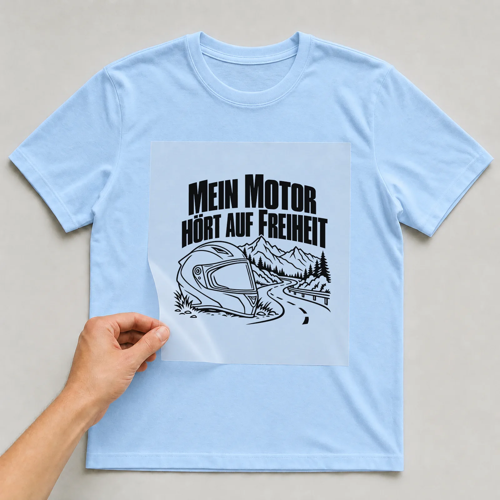 Bügelbild „Mein Motor hört auf Freiheit“ auf hellblauem T-Shirt, Folie wird aufgelegt