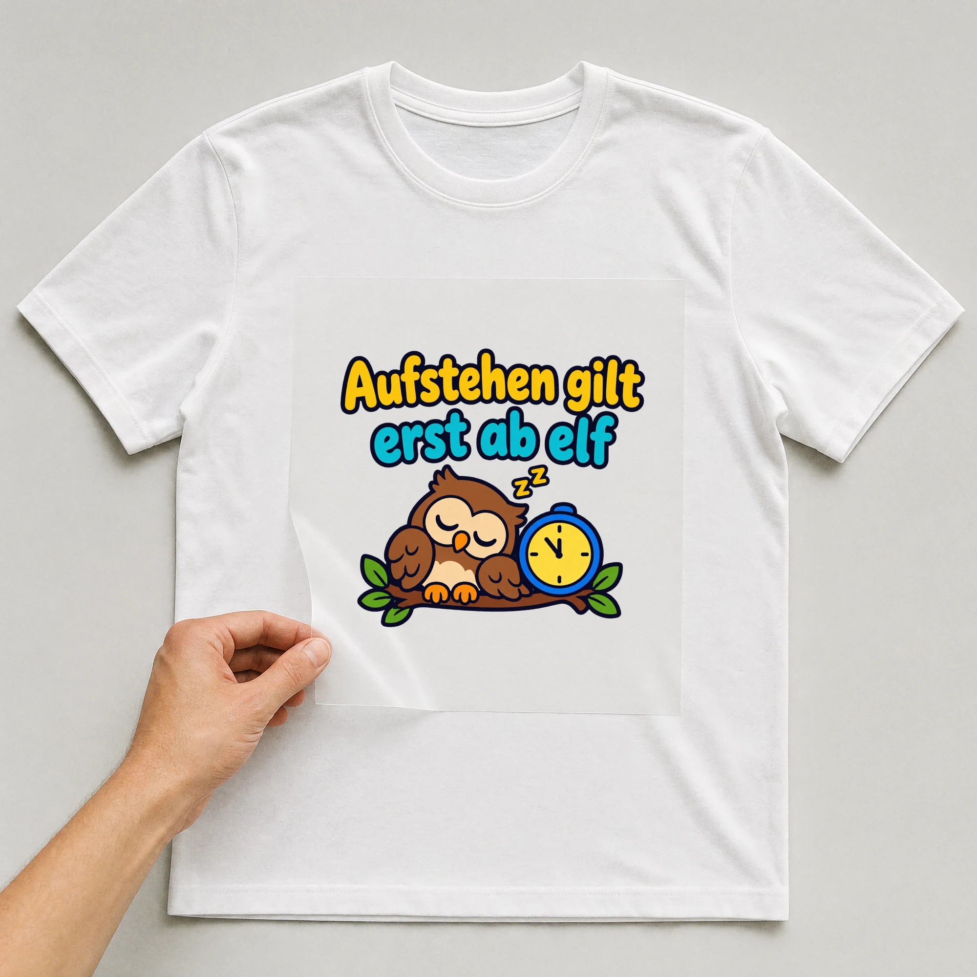 Bügelbild „Aufstehen gilt erst ab elf“ auf weißem T-Shirt, Folie wird aufgelegt