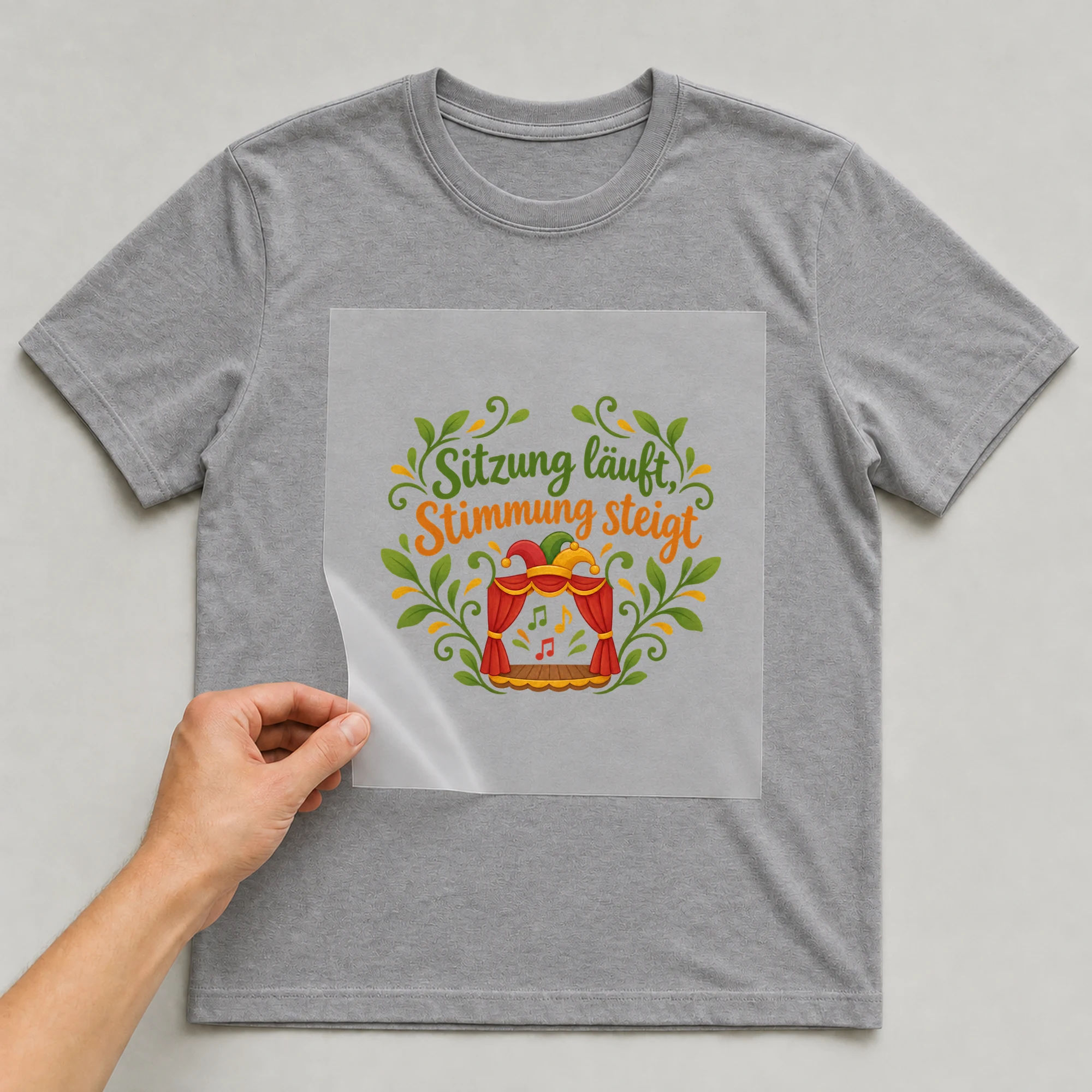 Bügelbild „Sitzung läuft, Stimmung steigt“ auf grauem T-Shirt, Folie wird aufgelegt