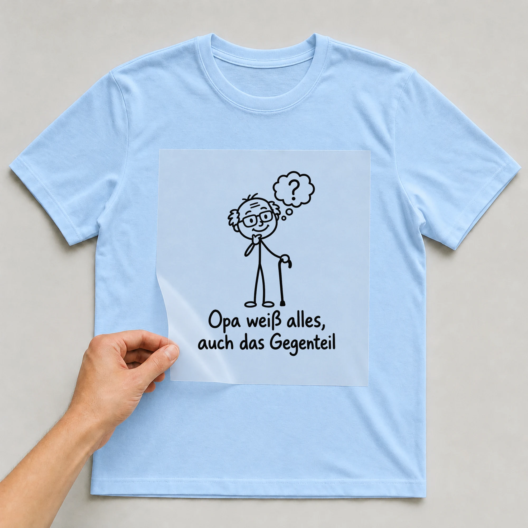 Bügelbild „Opa weiß alles, auch das Gegenteil“ auf babyblauem T-Shirt, Folie wird aufgelegt