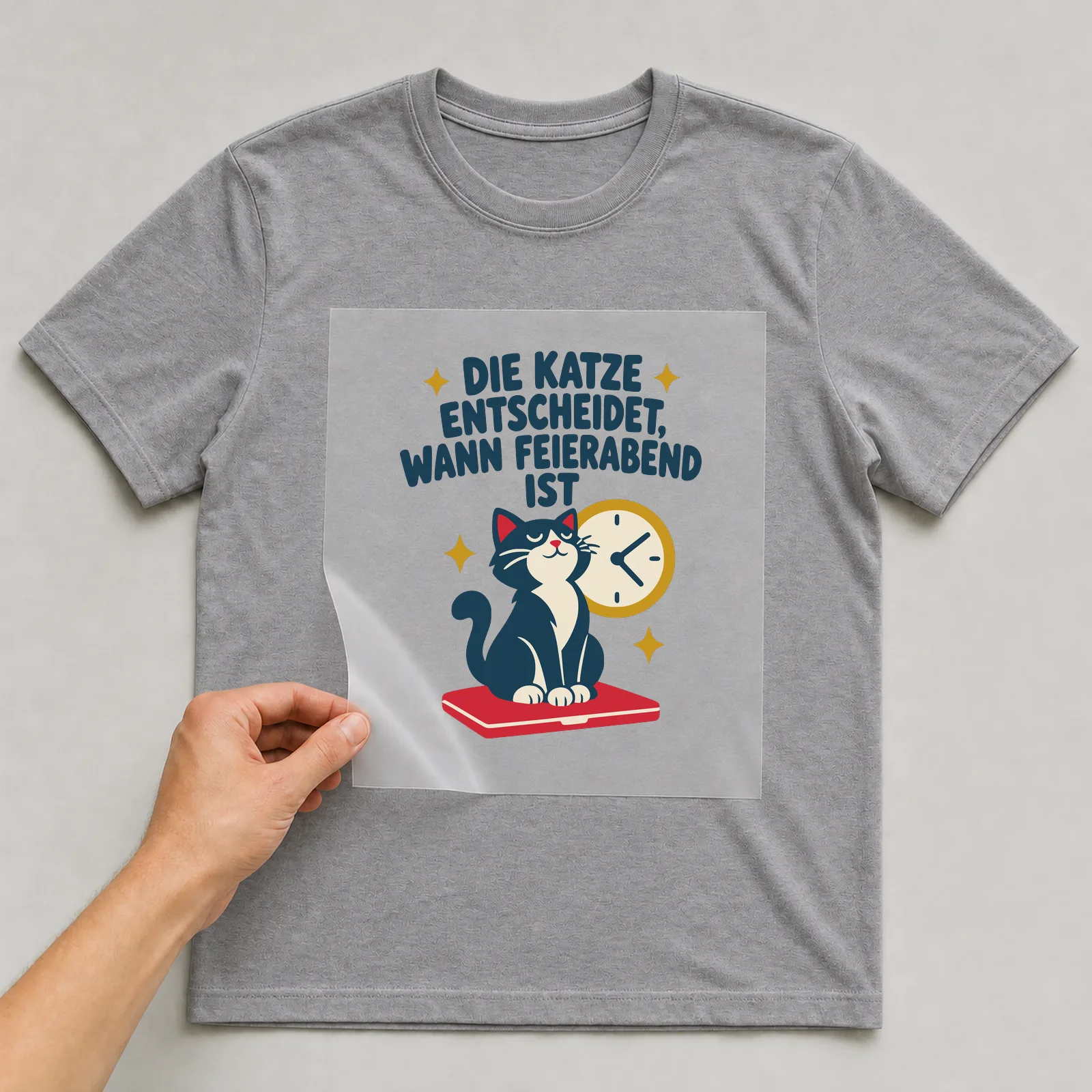 Bügelbild Die Katze entscheidet, wann Feierabend ist auf grauem T-Shirt, Folie wird aufgelegt