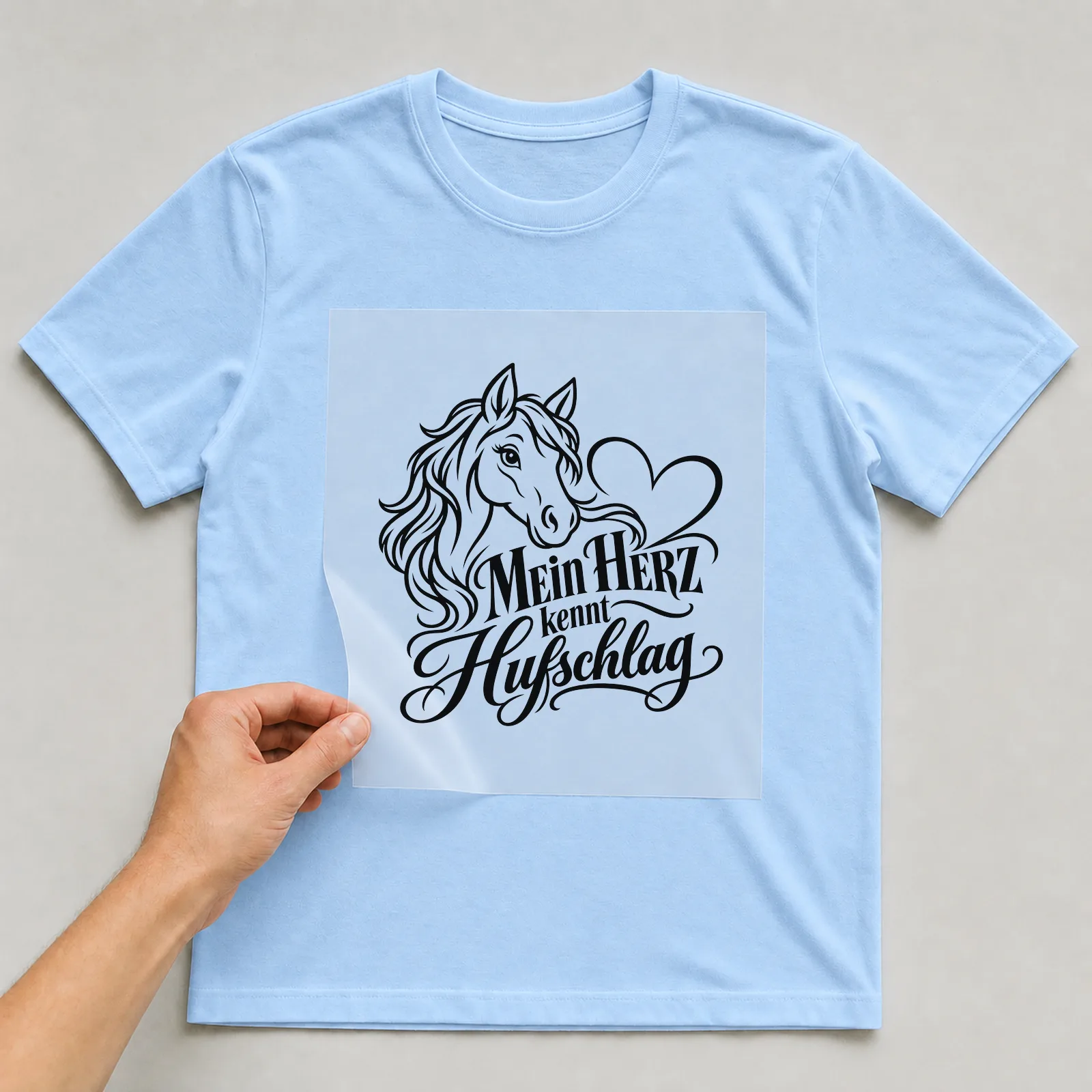 Bügelbild „Mein Herz kennt Hufschlag“ auf hellblauem T-Shirt, Folie wird aufgelegt