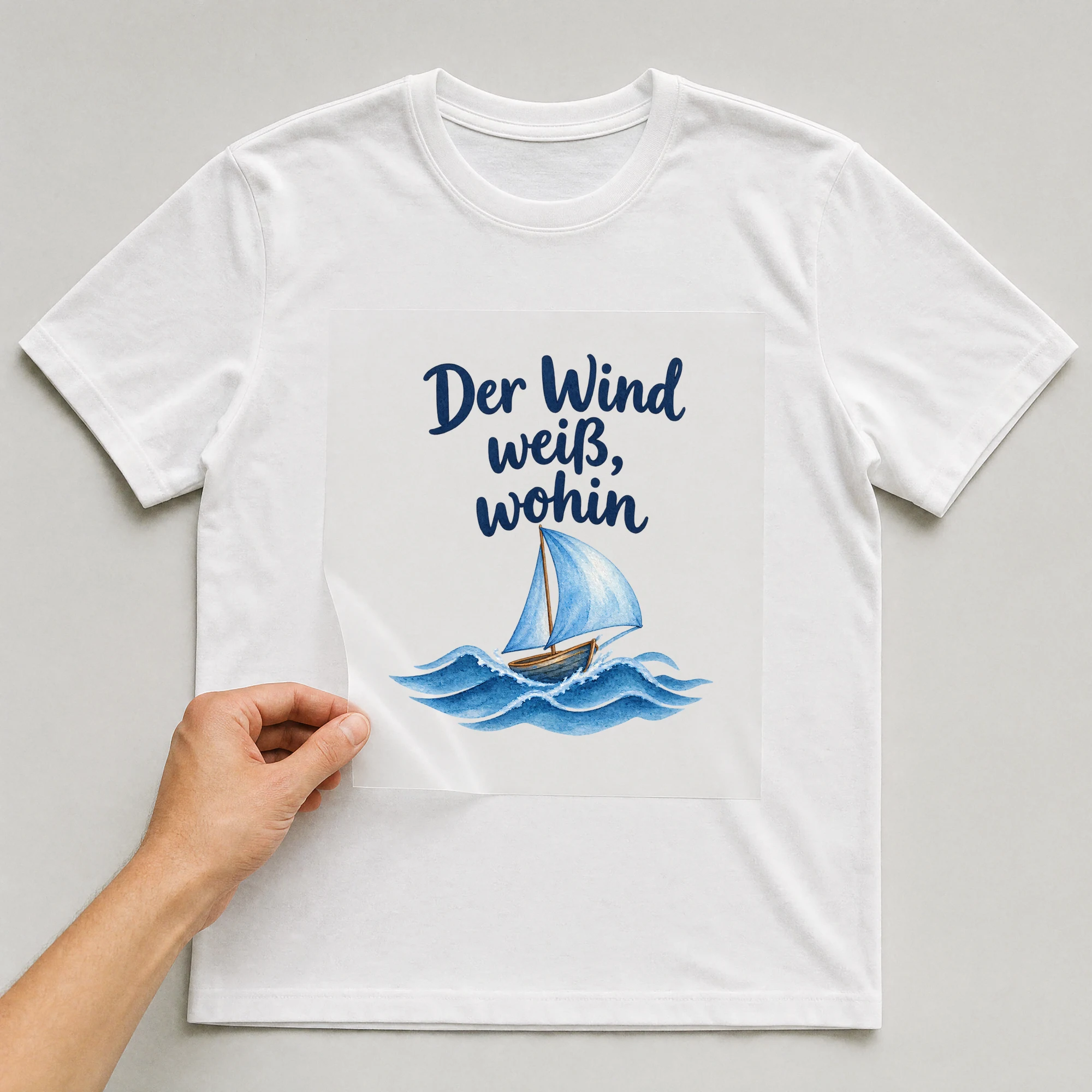 Bügelbild „Der Wind weiß, wohin“ auf weißem T-Shirt, Folie wird aufgelegt