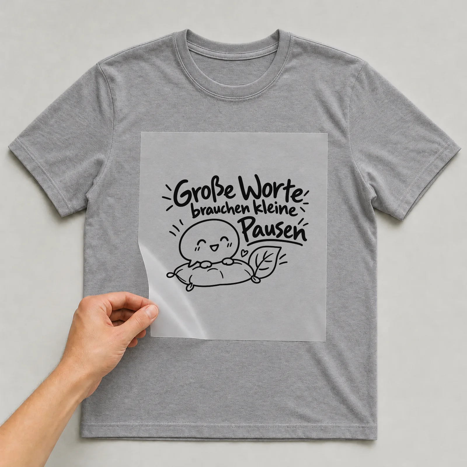 Bügelbild „Große Worte brauchen kleine Pausen“ auf grauem T-Shirt, Folie wird aufgelegt