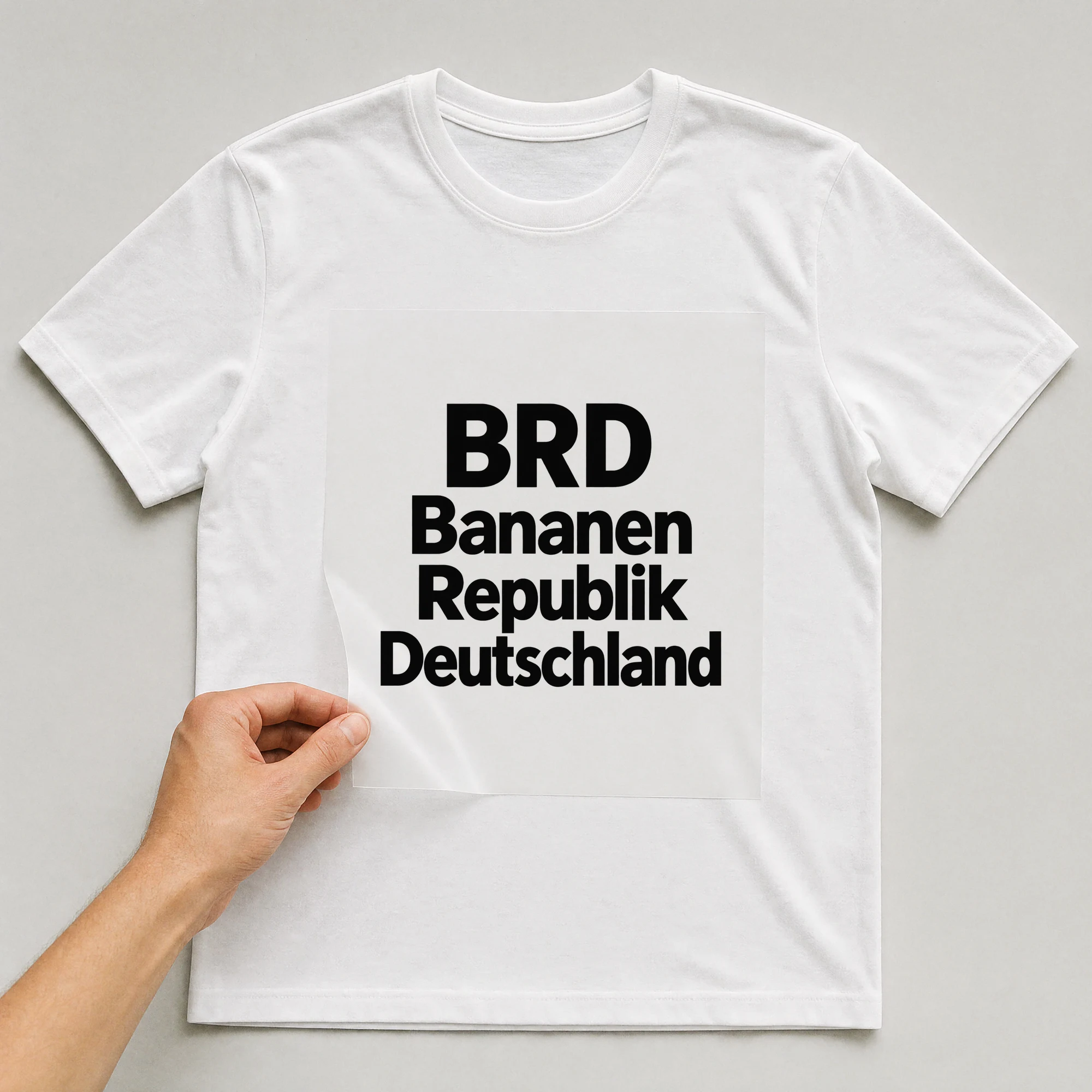 Bügelbild „BRD Bananen Republik Deutschland“ auf weißem T-Shirt, Folie wird aufgelegt