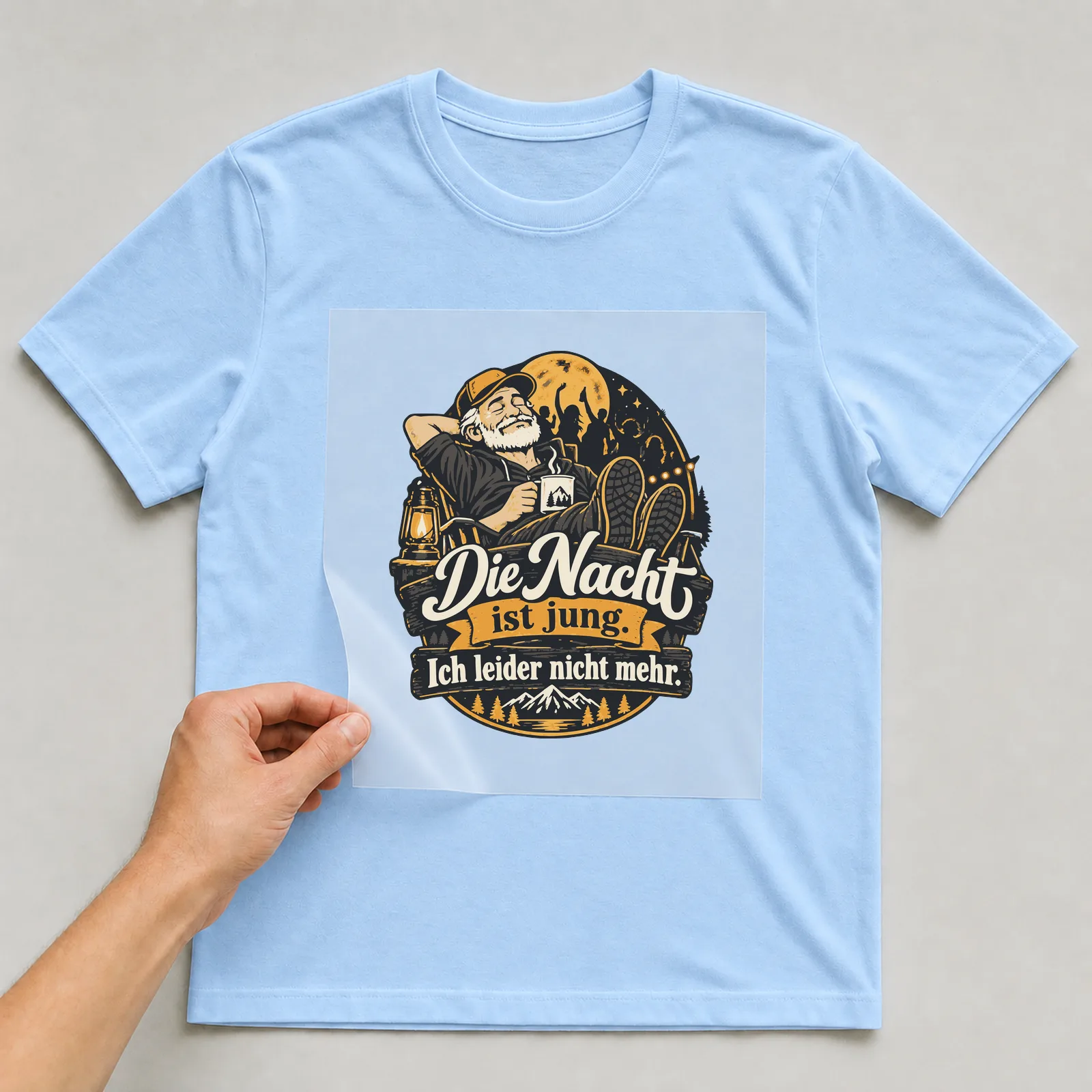 Bügelbild Die Nacht ist jung. Ich leider nicht mehr. auf hellblauem T-Shirt, Folie wird aufgelegt
