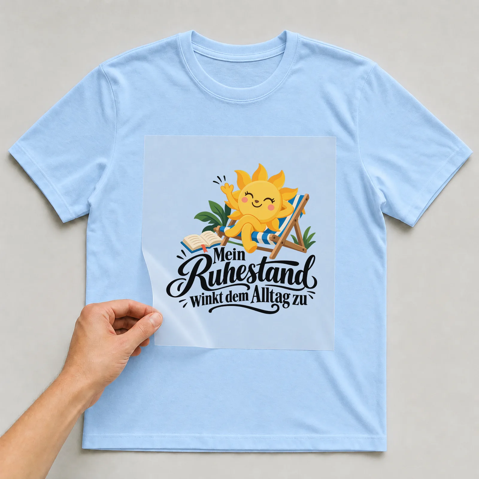 Bügelbild „Mein Ruhestand winkt dem Alltag zu“ auf hellblauem T-Shirt, Folie wird aufgelegt