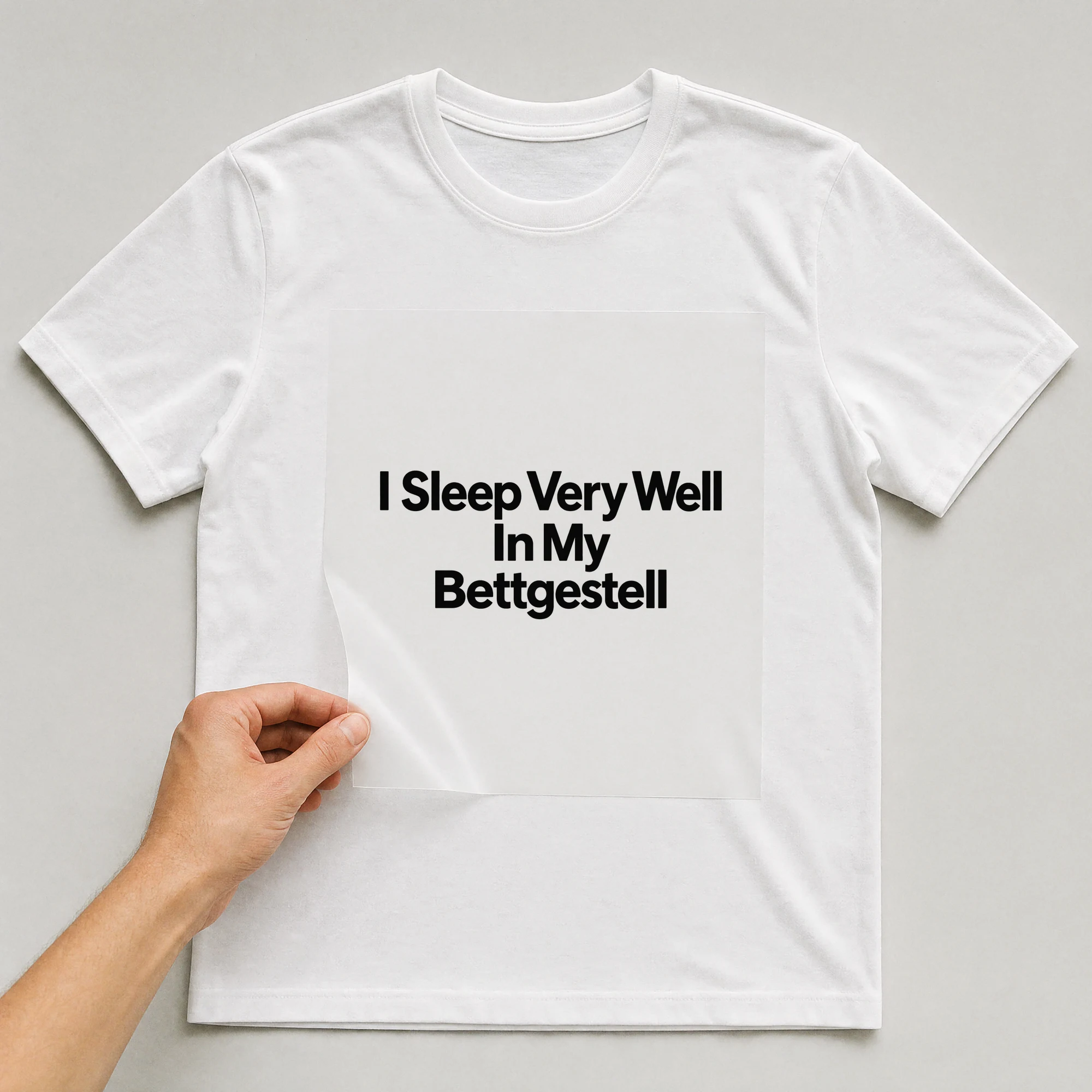 Bügelbild „I Sleep Very Well In My Bettgestell“ auf weißem T-Shirt, Folie wird aufgelegt