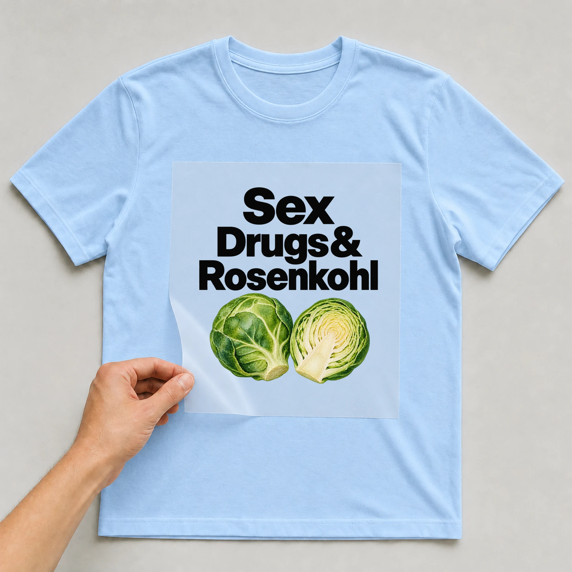 Bügelbild „Sex Drugs & Rosenkohl“ auf babyblauem T-Shirt, Folie wird aufgelegt
