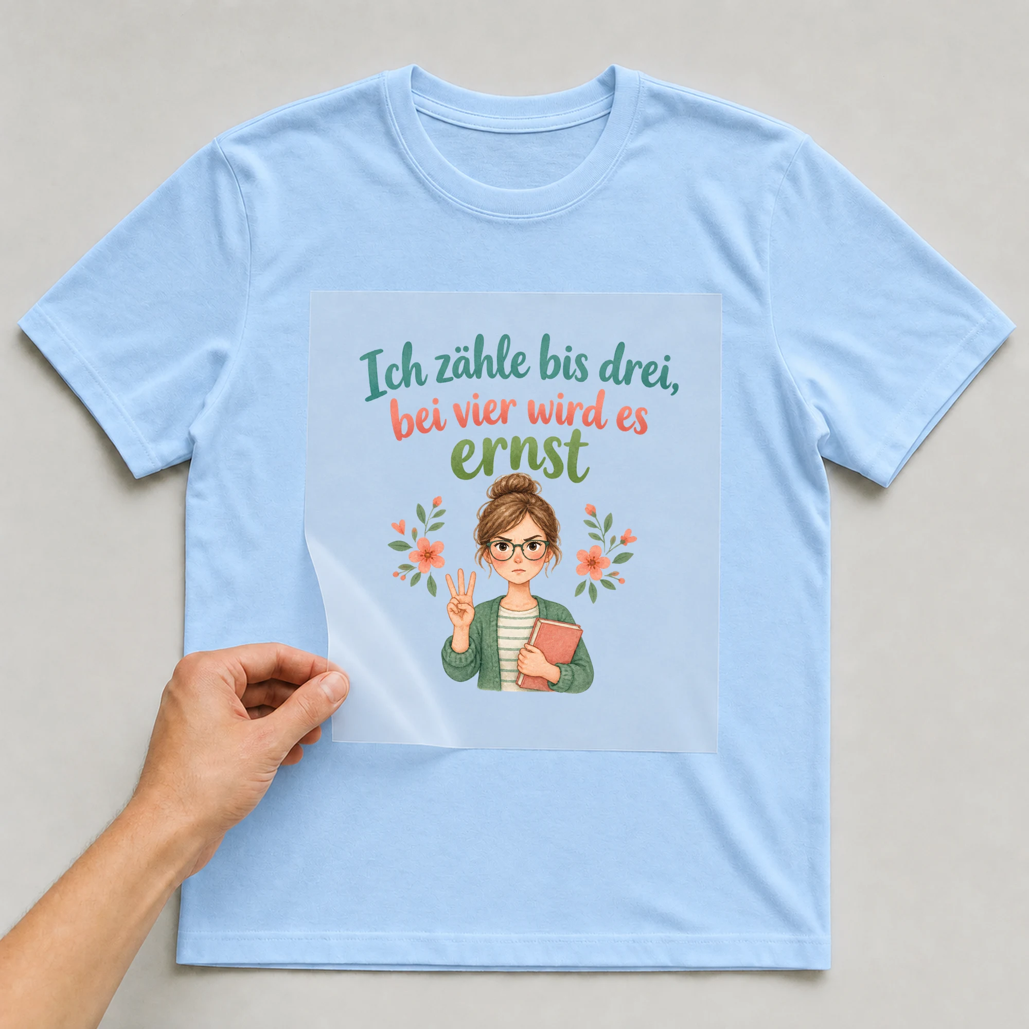 Bügelbild „Ich zähle bis drei, bei vier wird es ernst“ auf babyblauem T-Shirt, Folie wird aufgelegt
