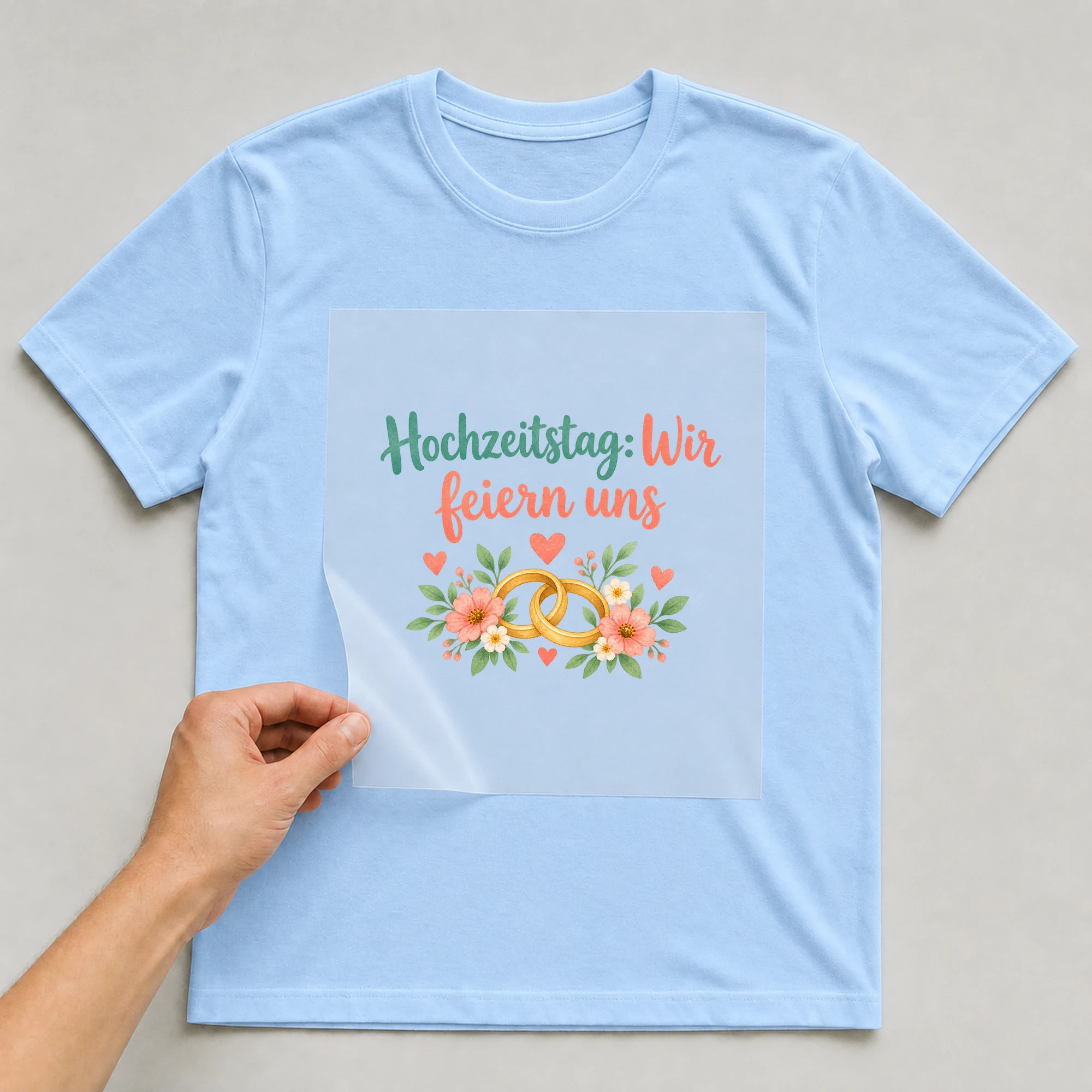 Bügelbild „Hochzeitstag: Wir feiern uns“ auf babyblauem T-Shirt, Folie wird aufgelegt