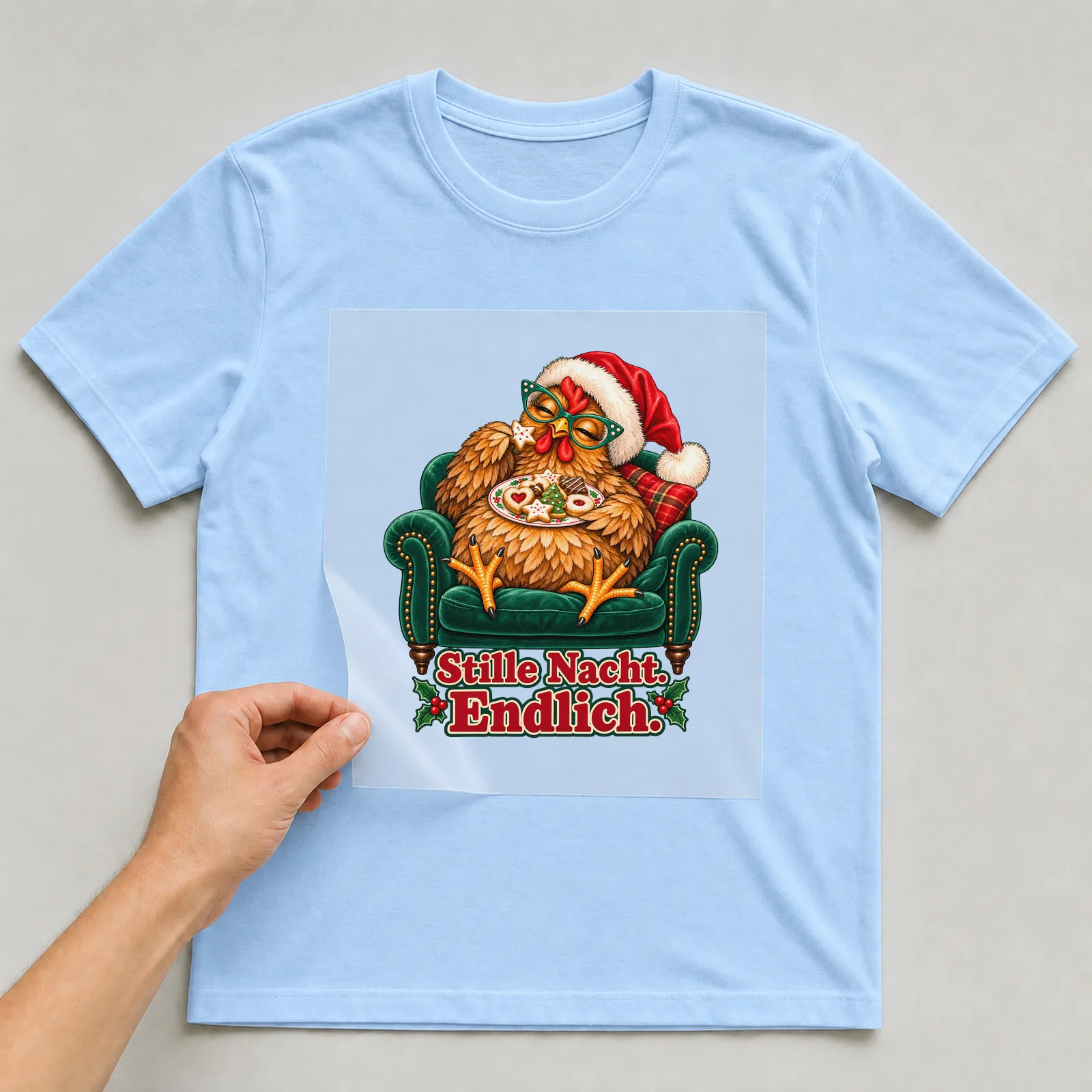Bügelbild Weihnachtshuhn im Sessel auf hellblauem T-Shirt, Folie wird aufgelegt