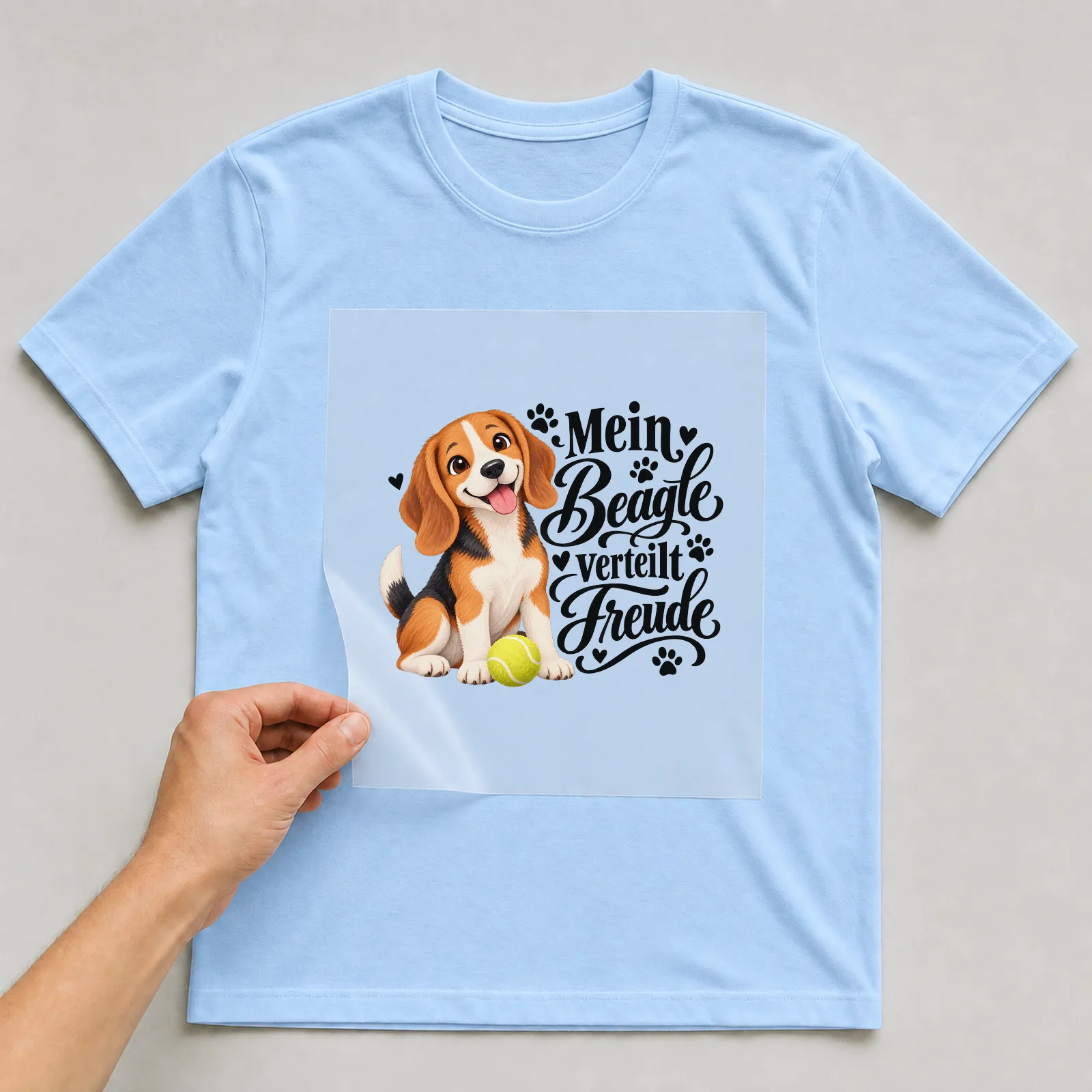 Bügelbild „Mein Beagle verteilt Freude“ auf hellblauem T-Shirt, Folie wird aufgelegt