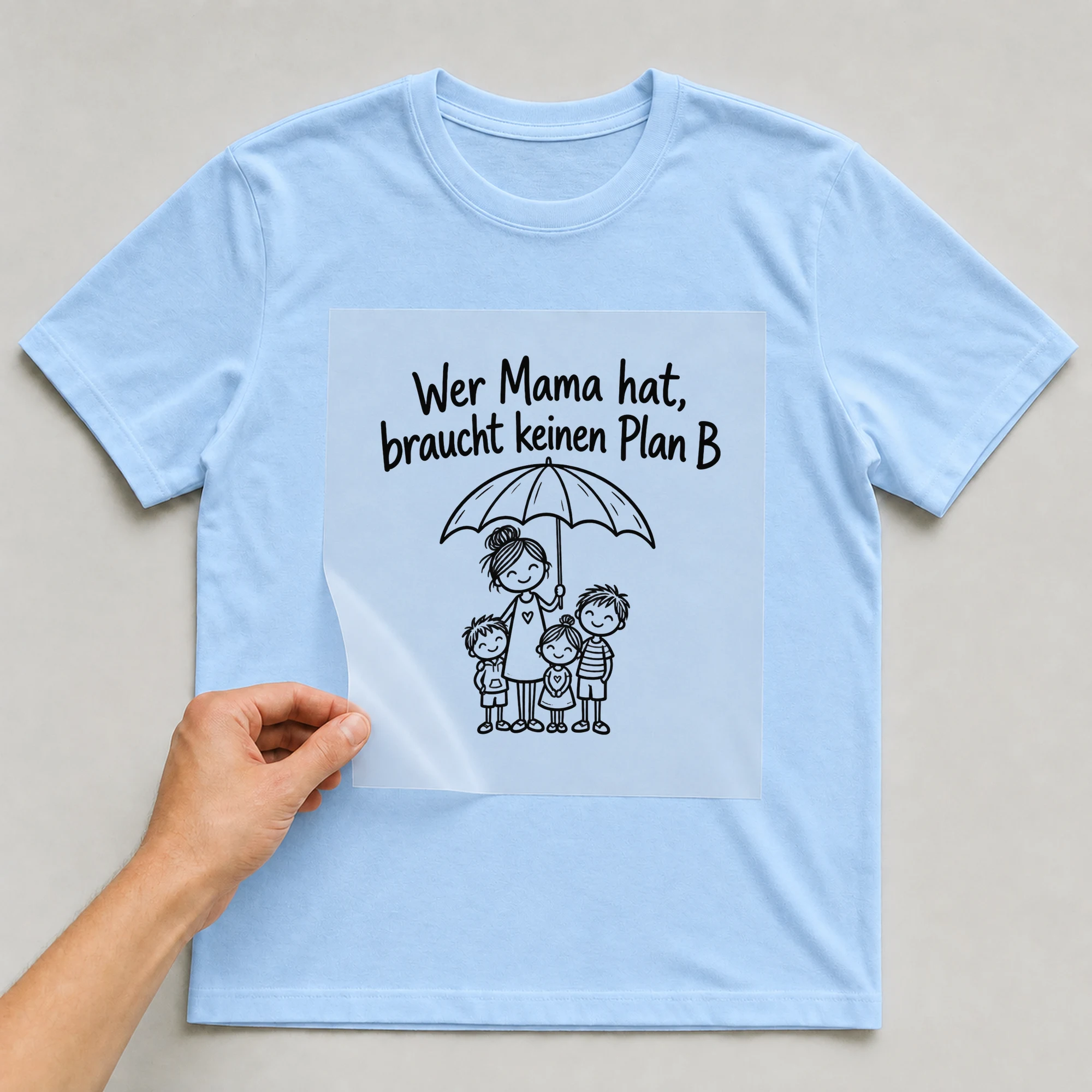 Bügelbild „Wer Mama hat, braucht keinen Plan B“ auf babyblauem T-Shirt, Folie wird aufgelegt
