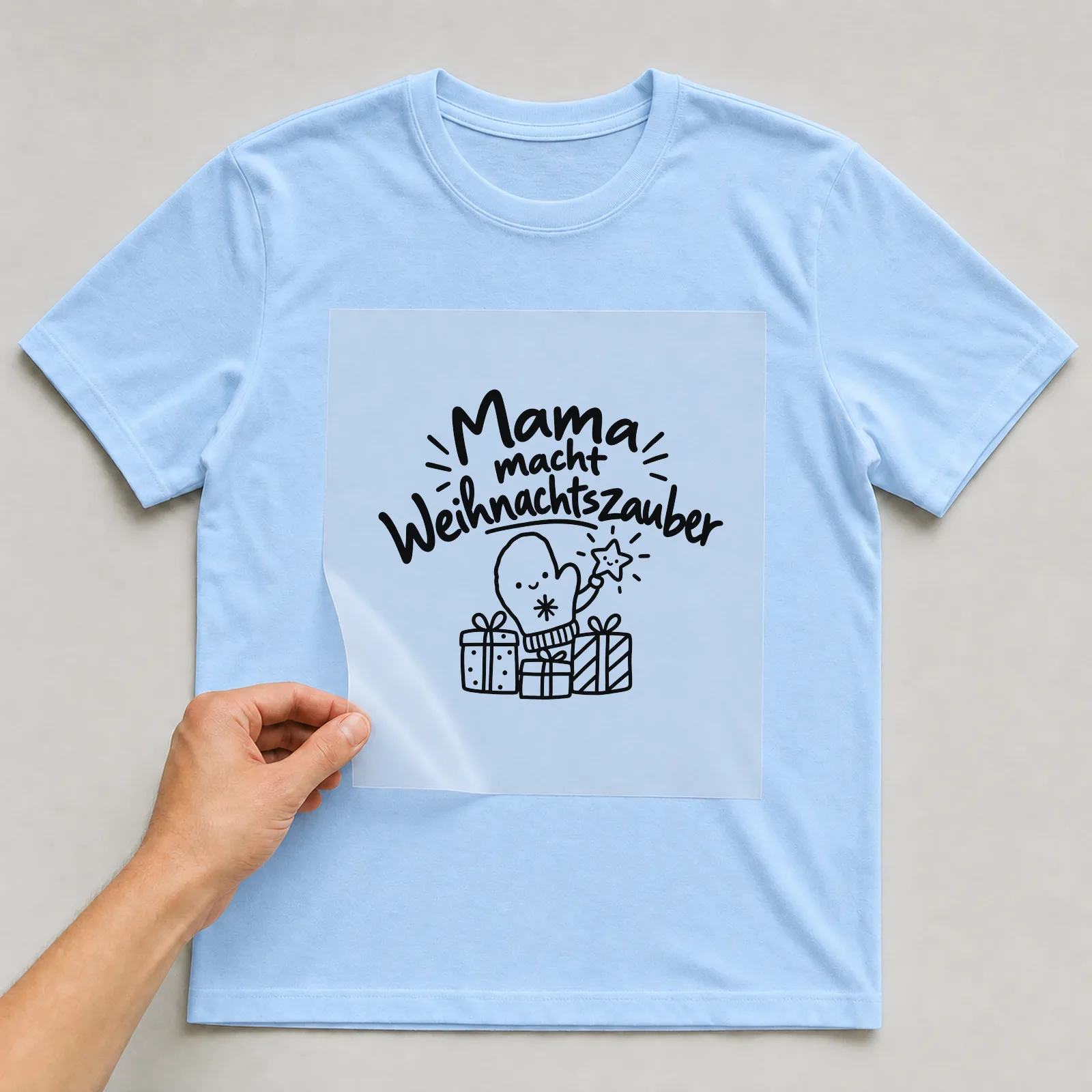 Bügelbild „Mama macht Weihnachtszauber“ auf hellblauem T-Shirt, Folie wird aufgelegt