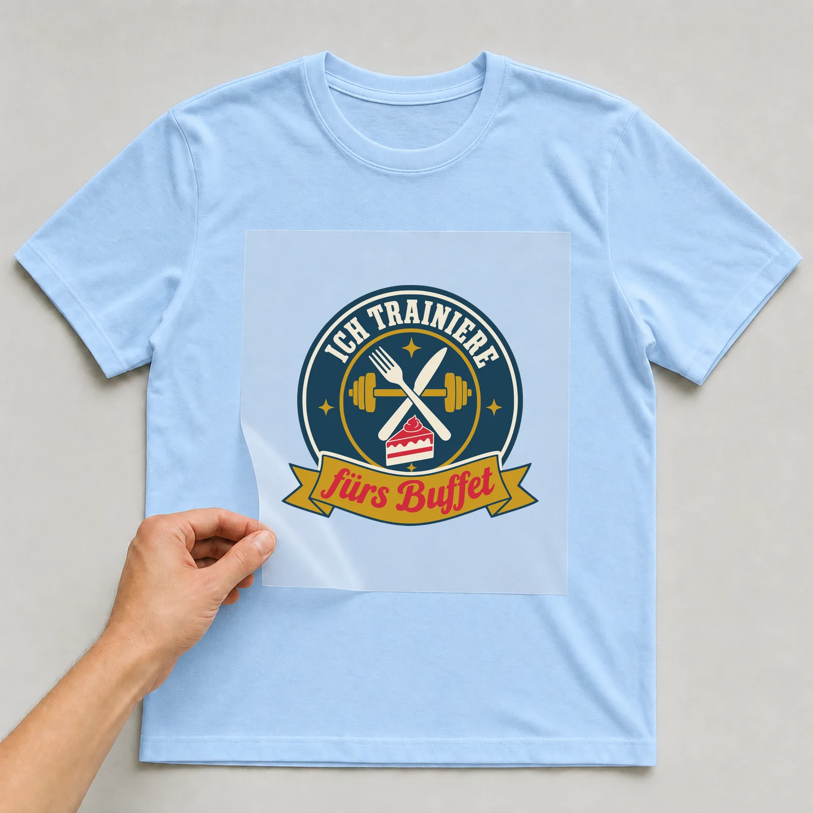 Bügelbild Ich trainiere fürs Buffet auf hellblauem T-Shirt, Folie wird aufgelegt
