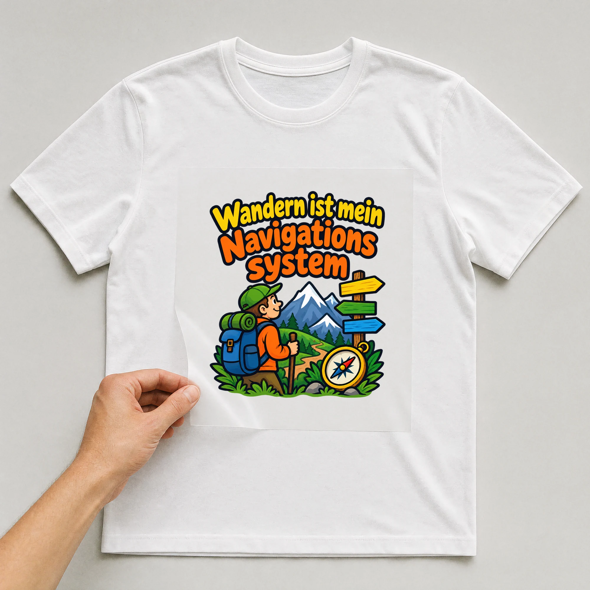 Bügelbild „Wandern ist mein Navigationssystem“ auf weißem T-Shirt, Folie wird aufgelegt