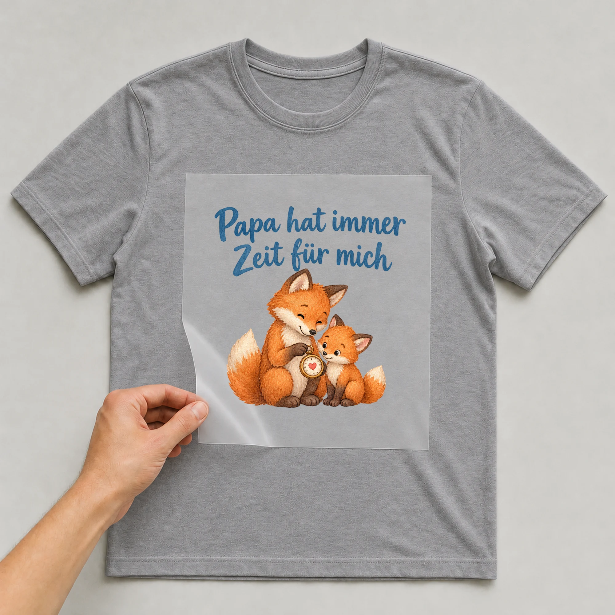 Bügelbild „Papa hat immer Zeit für mich“ auf grauem T-Shirt, Folie wird aufgelegt