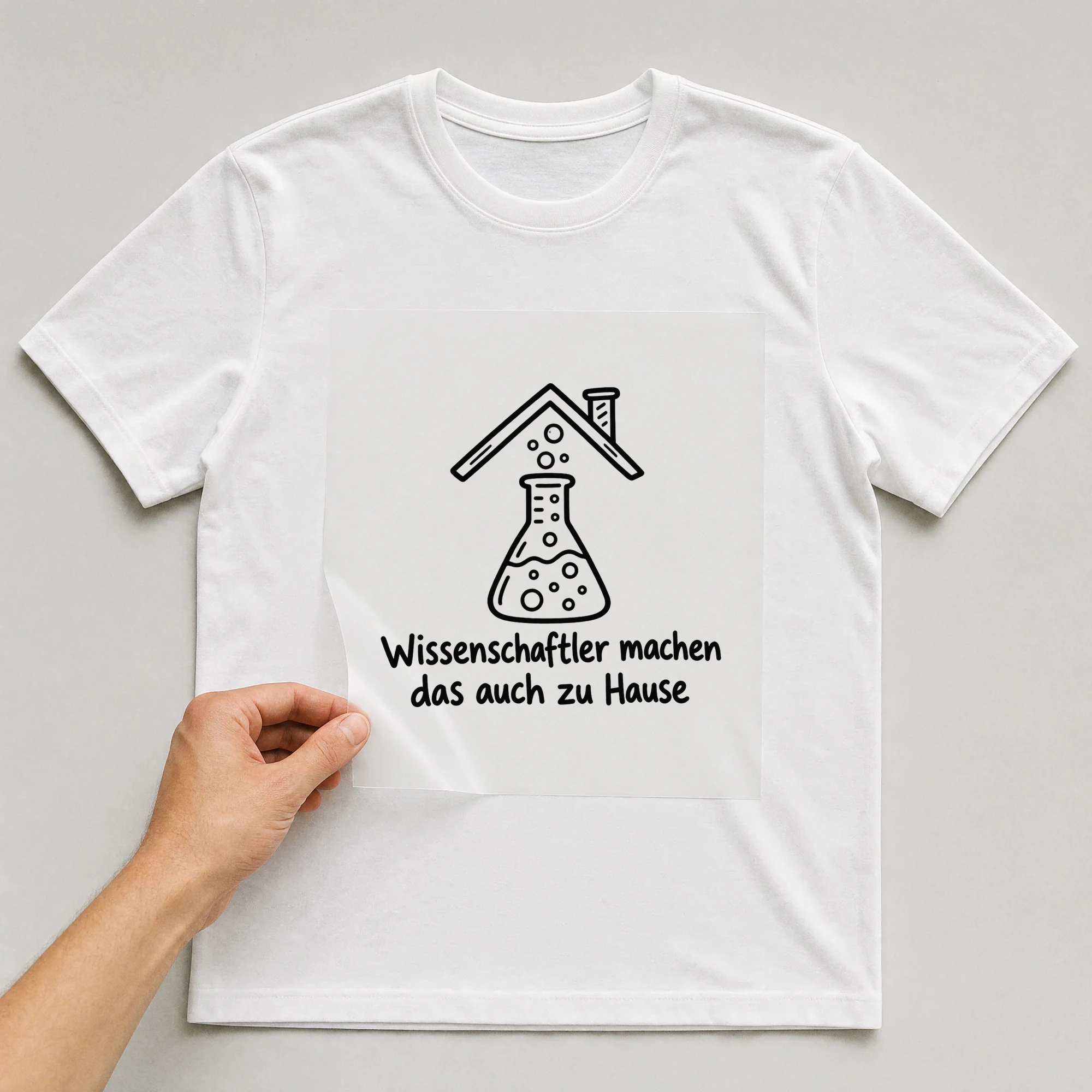 Bügelbild „Wissenschaftler machen das auch zu Hause“ auf weißem T-Shirt, Folie wird aufgelegt